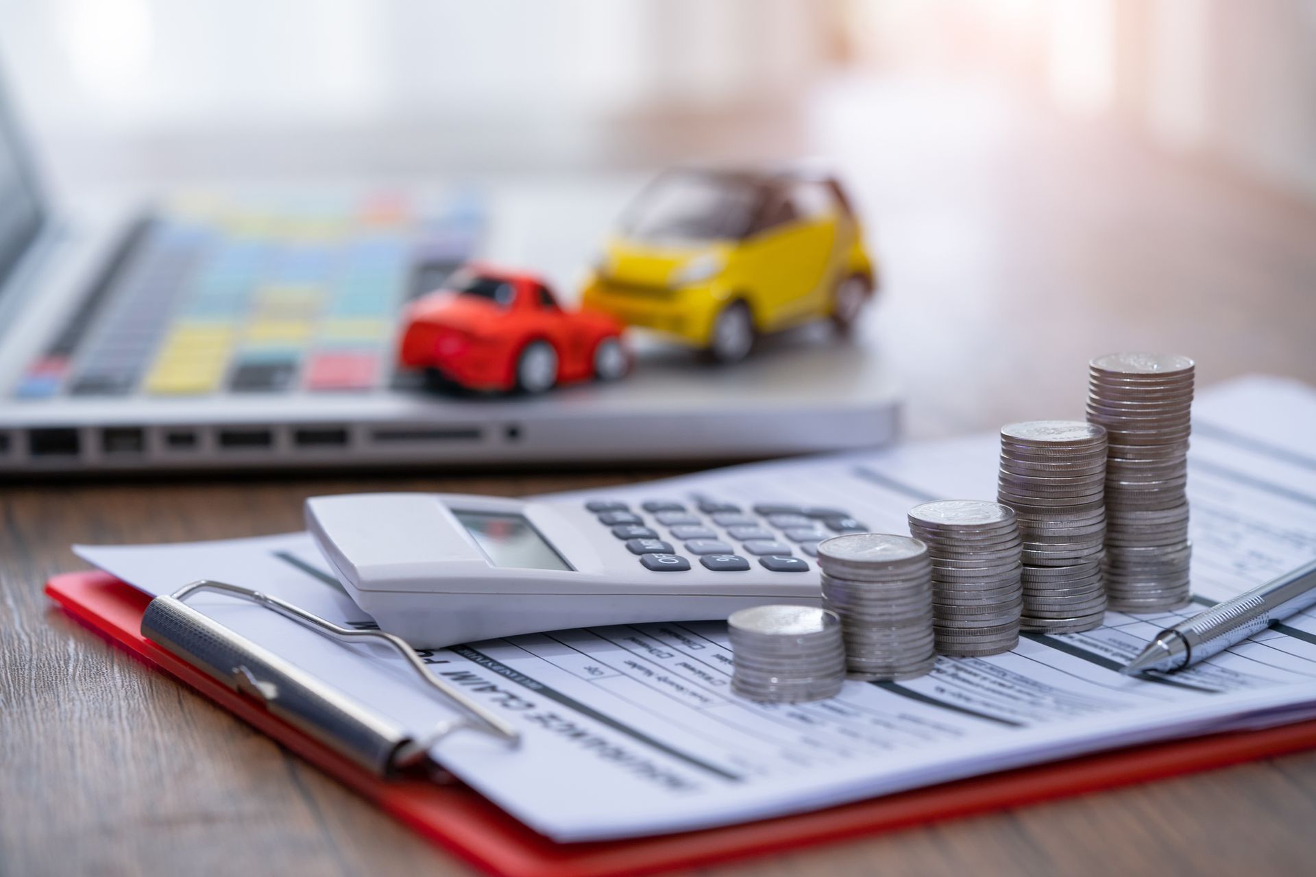 Stacks of coins on financial documents with calculator, pen, and toy cars. Stacks of coins on financial documents with calculator, pen, and toy cars.