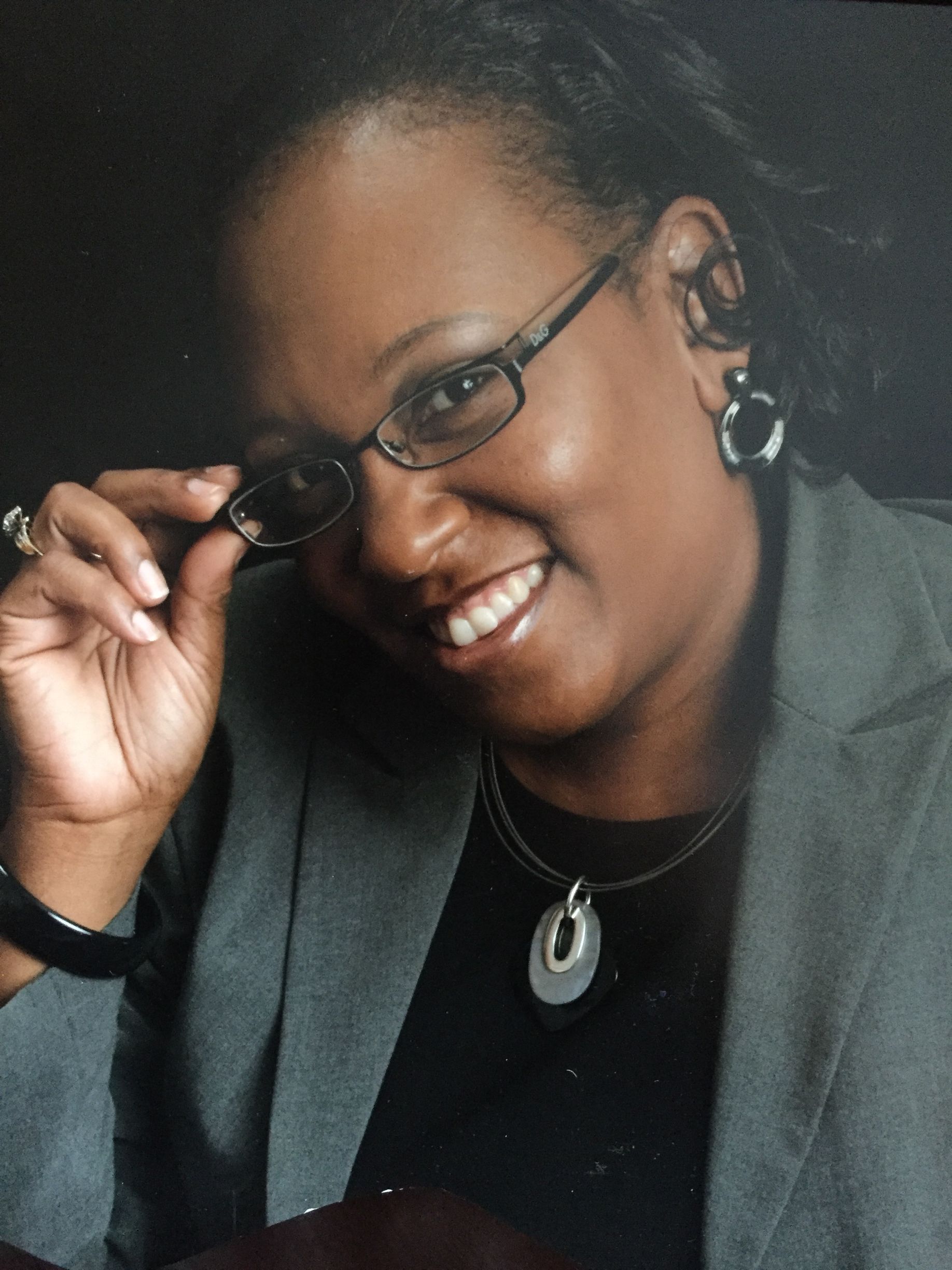 A woman wearing glasses and a black shirt is smiling