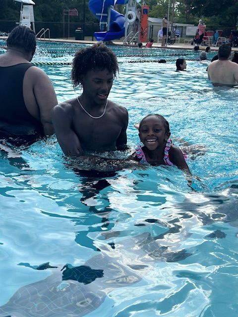 A man and a little girl are swimming in a pool.