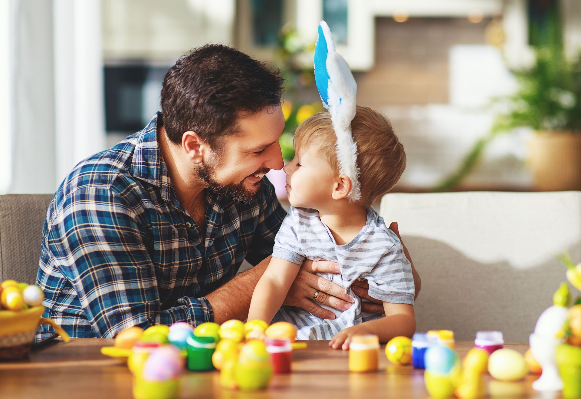 A man and a little boy are sitting at a table with easter eggs.