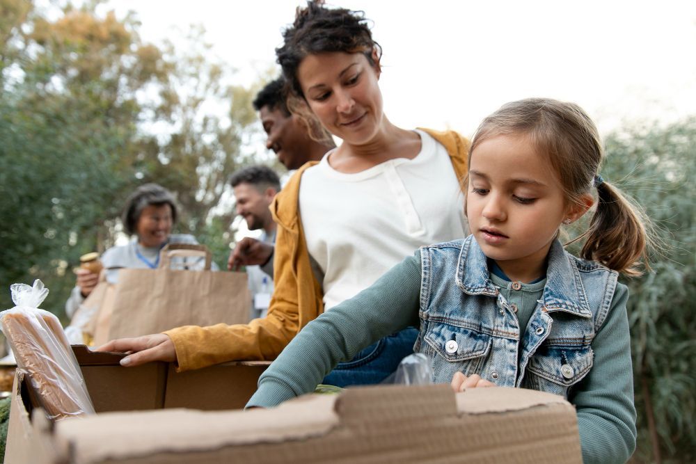 A woman and a little girl are standing next to a pile of cardboard boxes.
