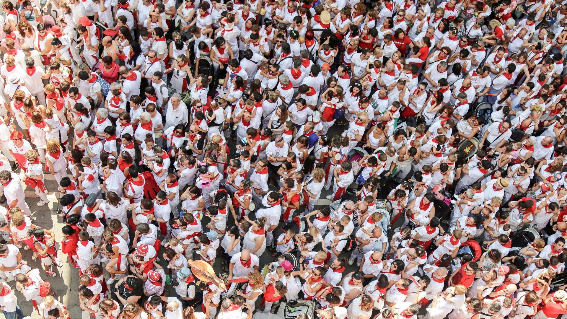 An aerial view of a large crowd of people wearing white shirts and red hats.