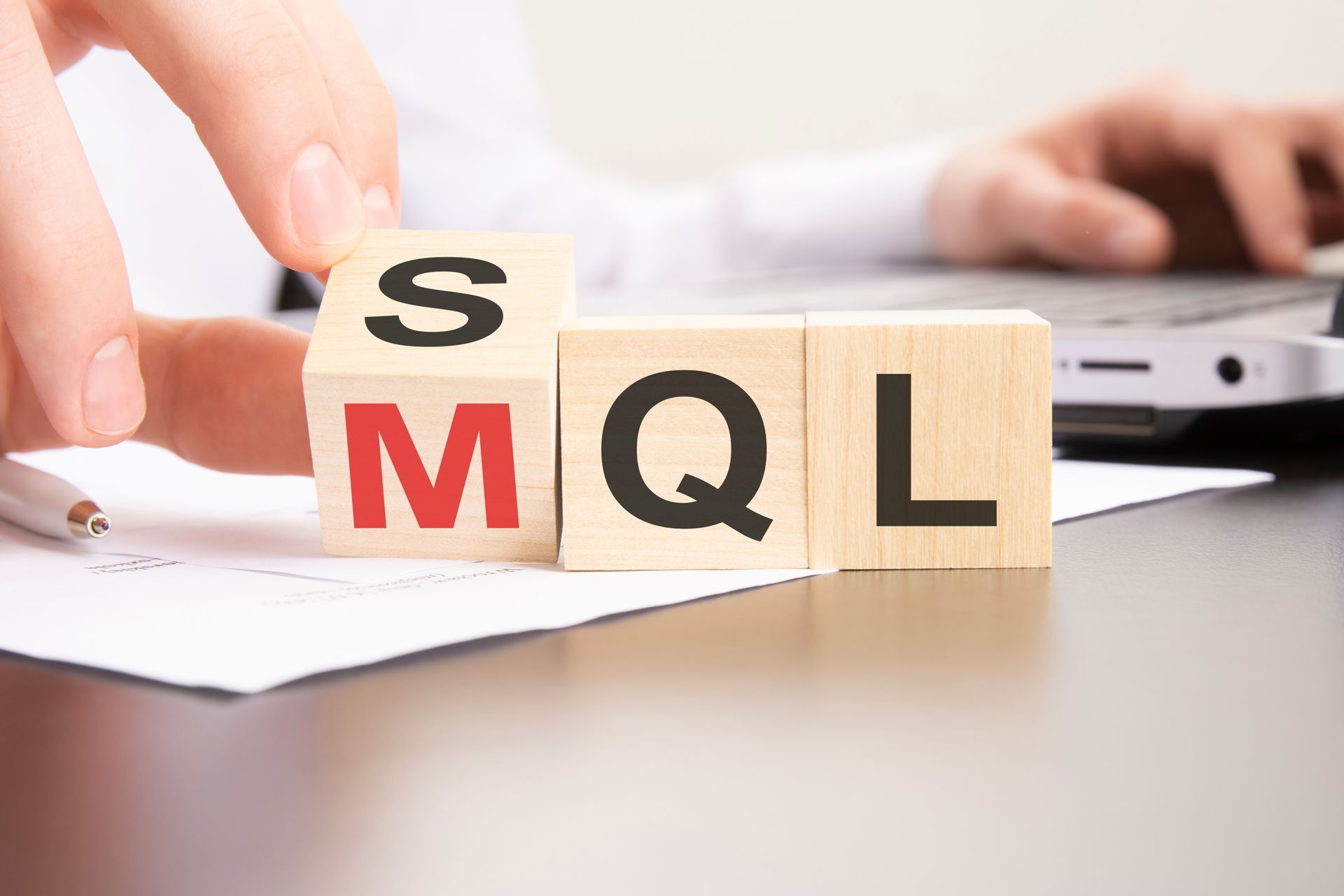 A person is holding a wooden block with the word mql on it.