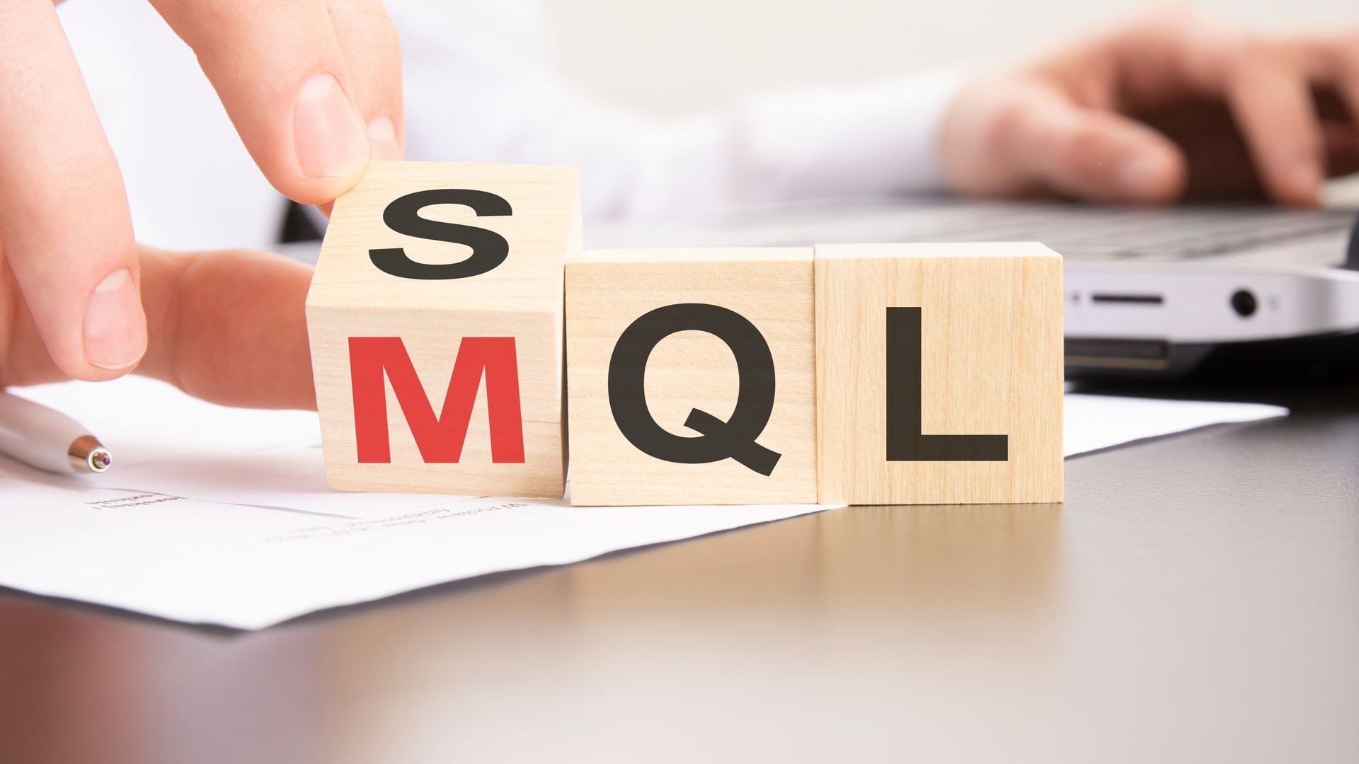 A person is holding a wooden block with the word mql on it.