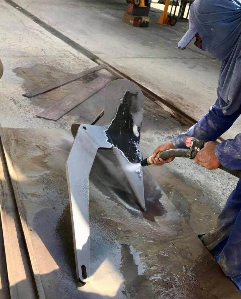 A man is sanding a piece of metal with a sander.