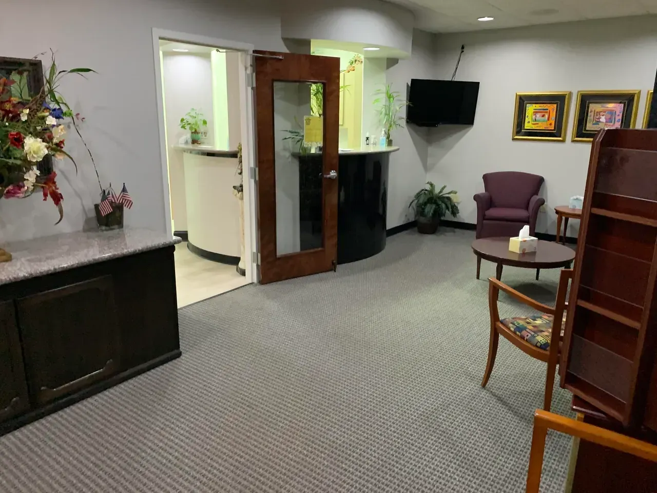 A waiting room with chairs a table and a television