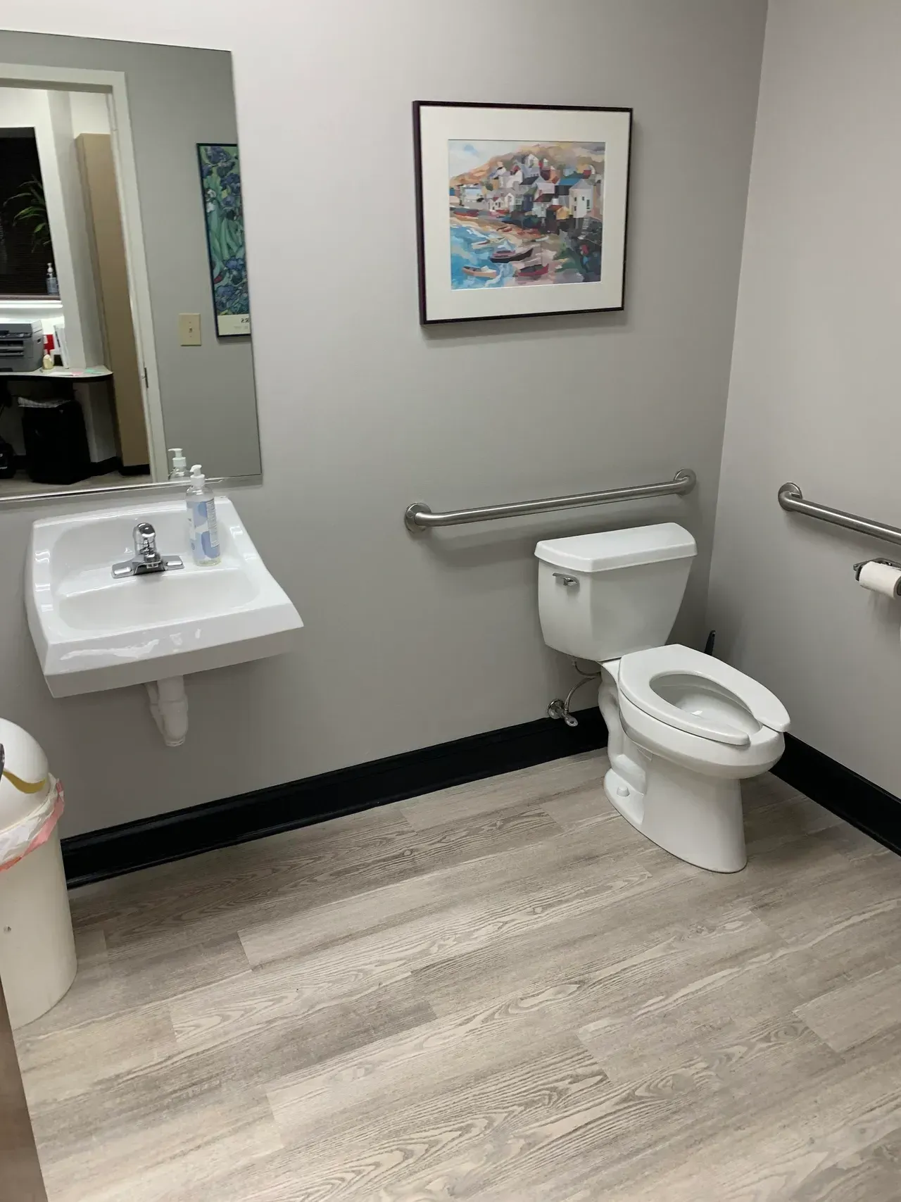 A bathroom with a toilet , sink and mirror.