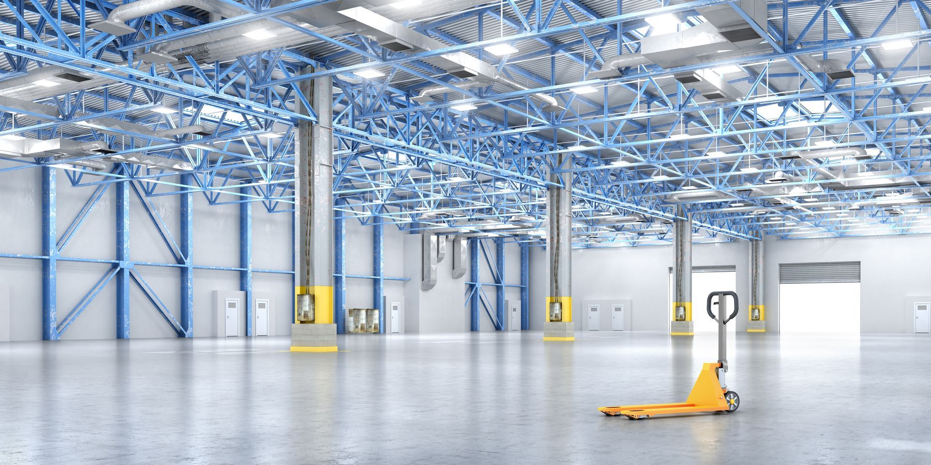An empty warehouse with a yellow hand truck in the middle.