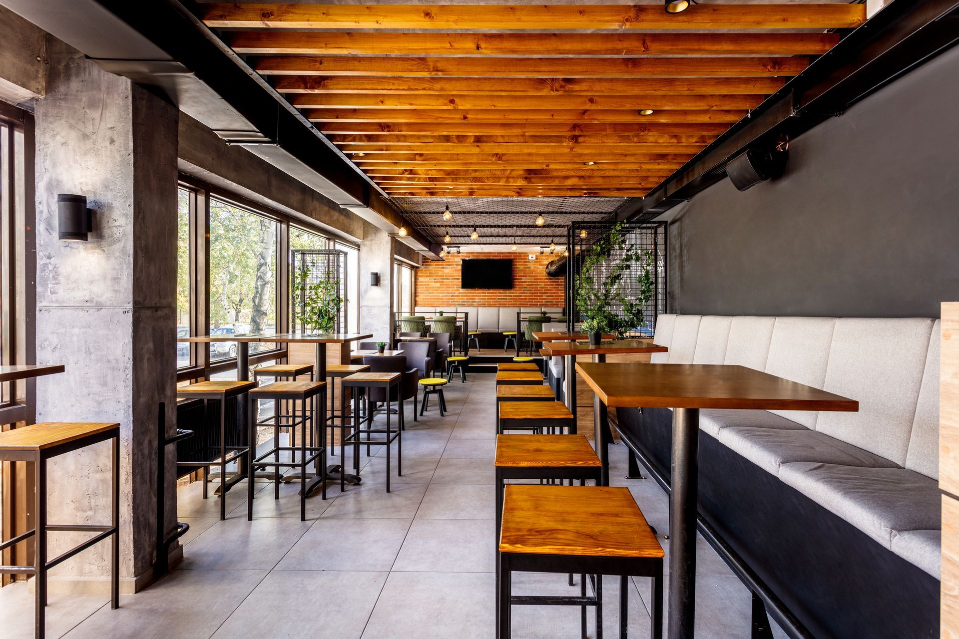 A restaurant with tables and chairs and a television on the wall.