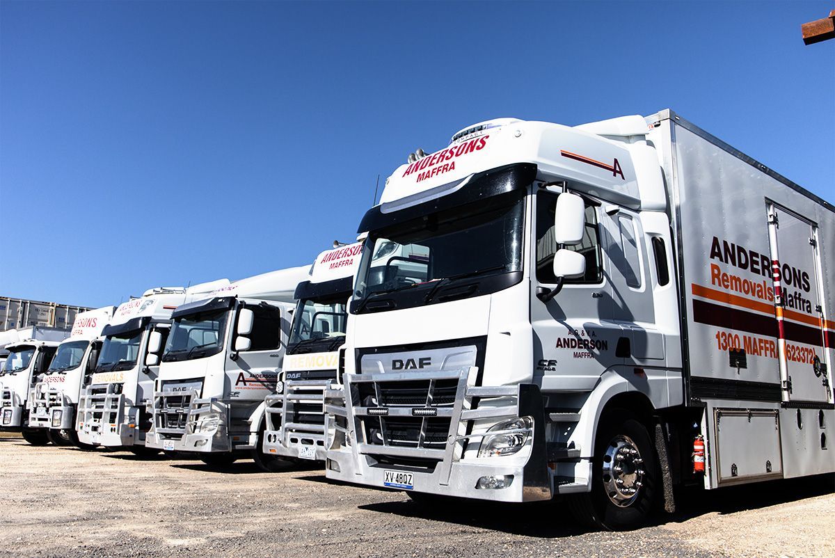 A row of white trucks are parked in a parking lot.