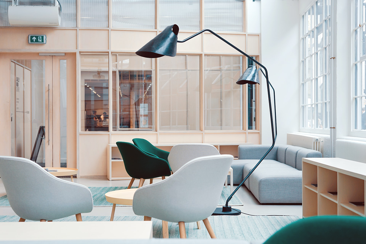 A living room with a couch , chairs , tables and a lamp.