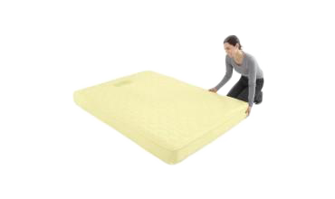 A woman is kneeling over a yellow mattress