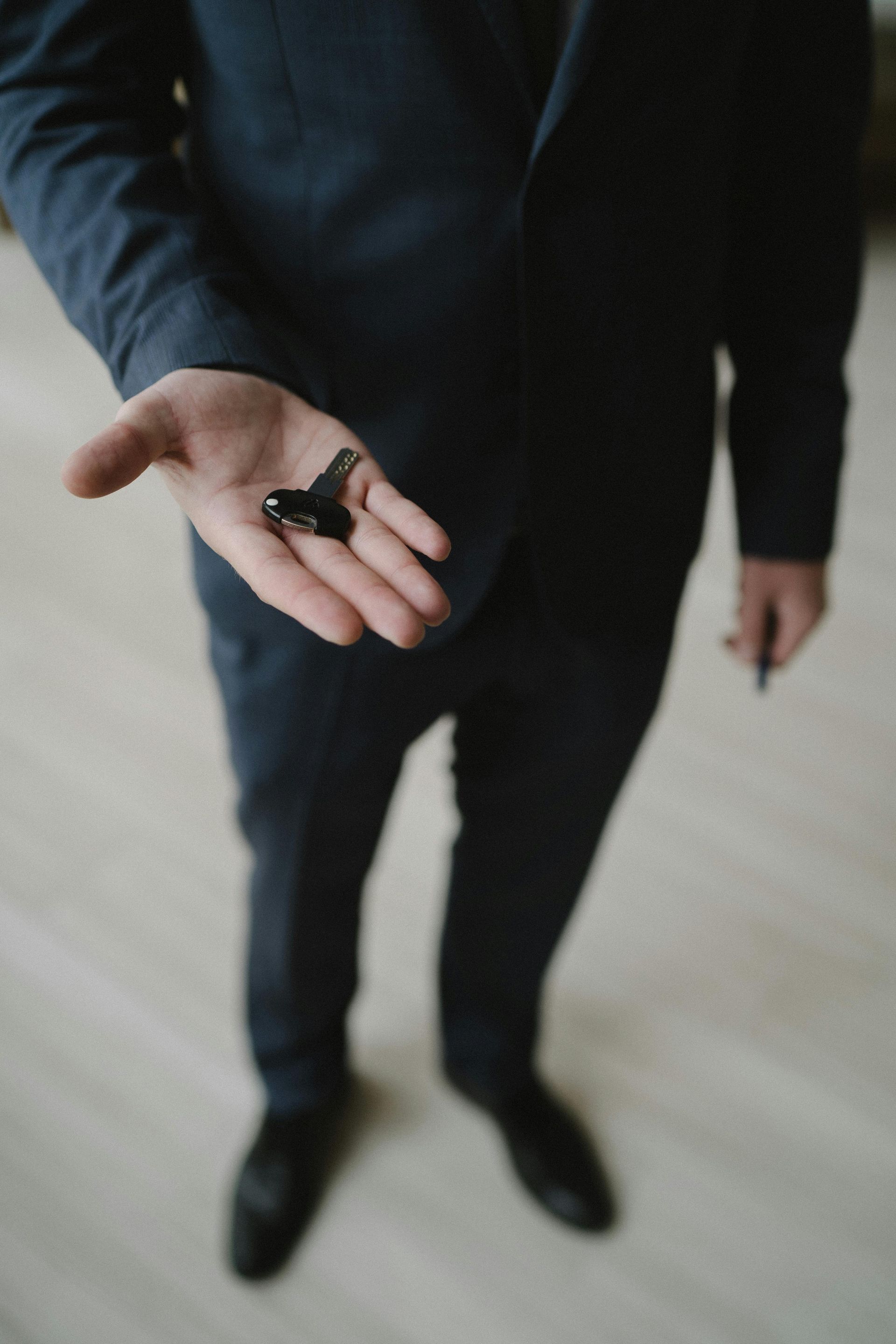 A man in a suit is holding a key in his hand.
