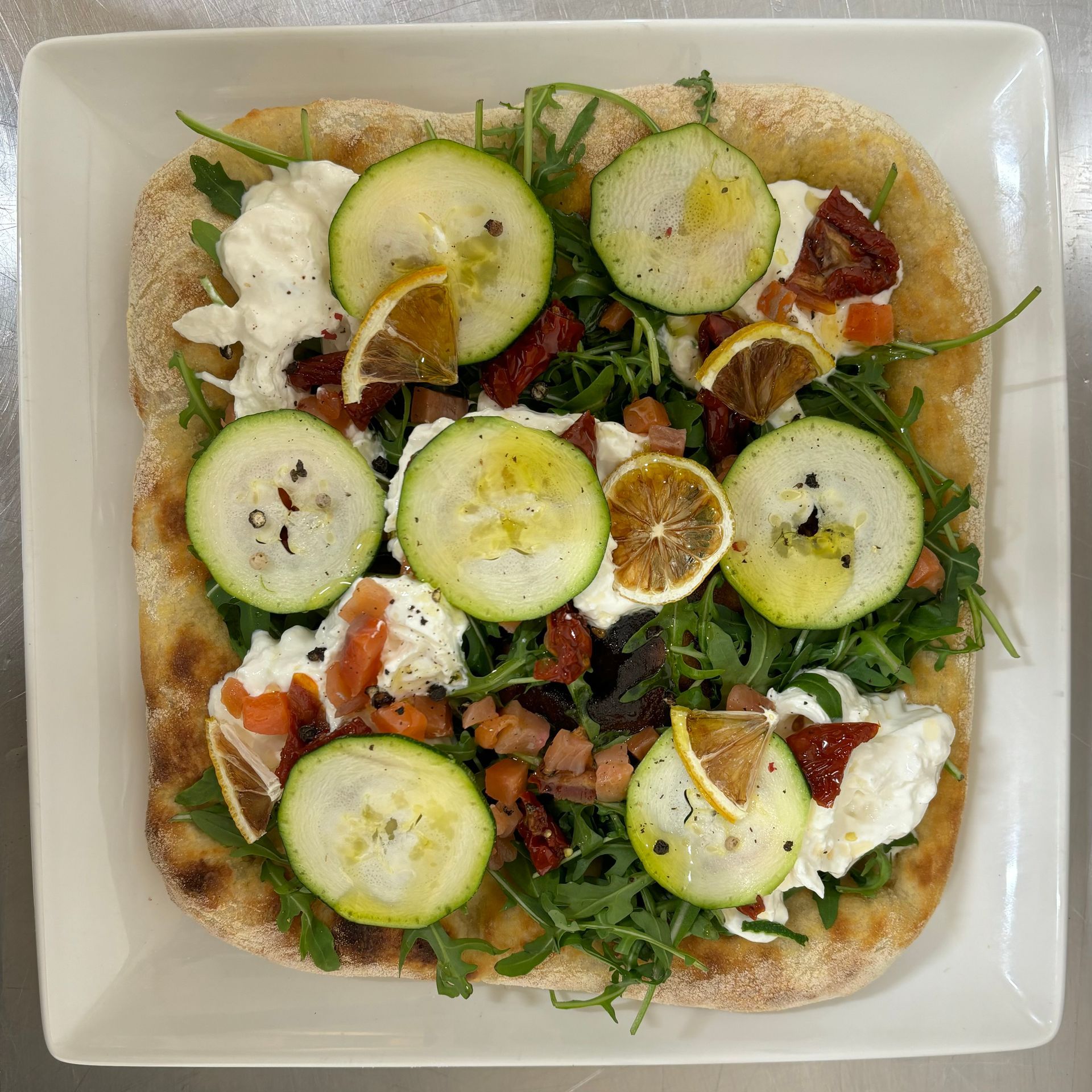 Una pizza con tante verdure sopra su un piatto bianco