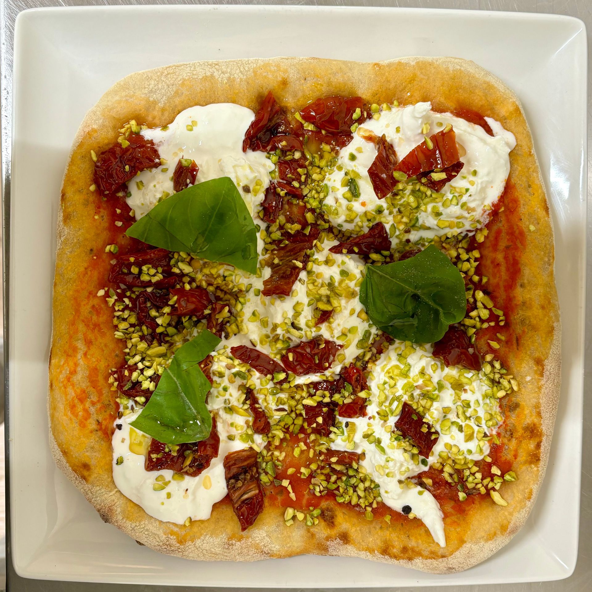 Una pizza con tanti condimenti è servita su un piatto bianco.