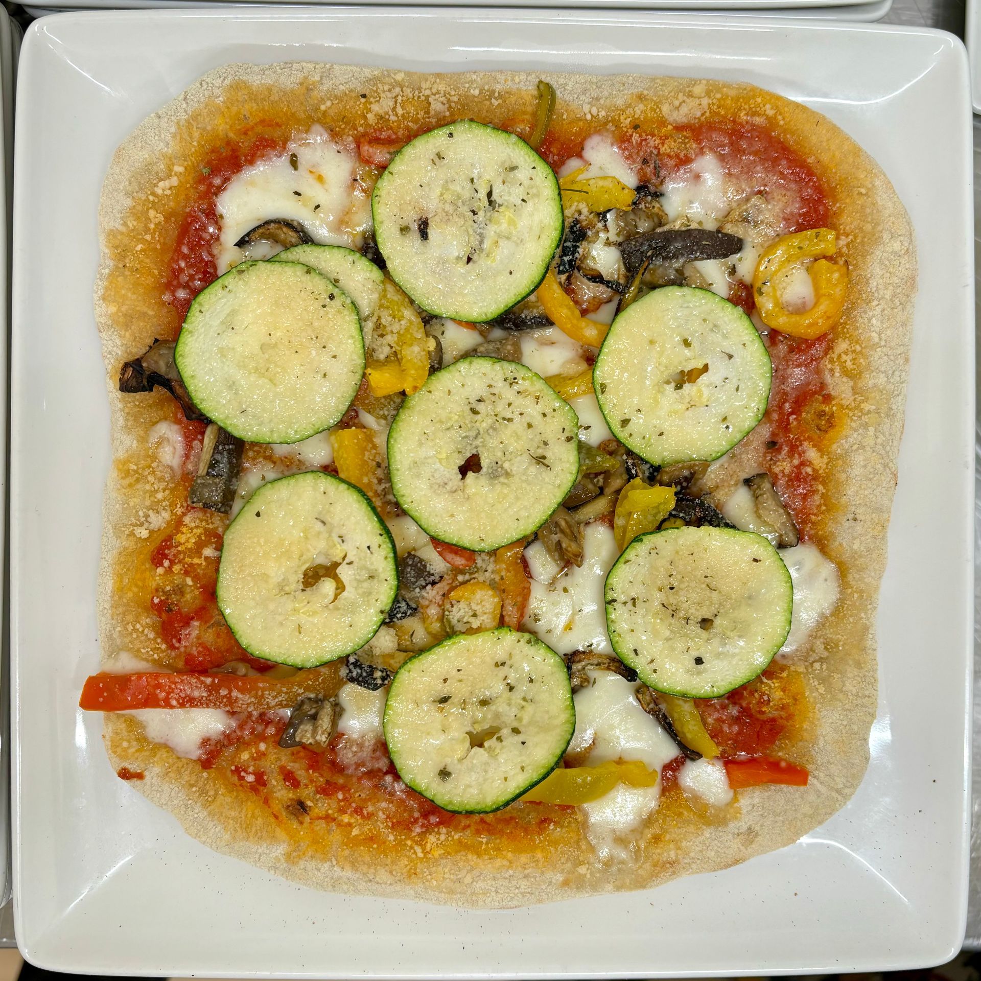 Una pizza con zucchine e peperoni su un piatto bianco