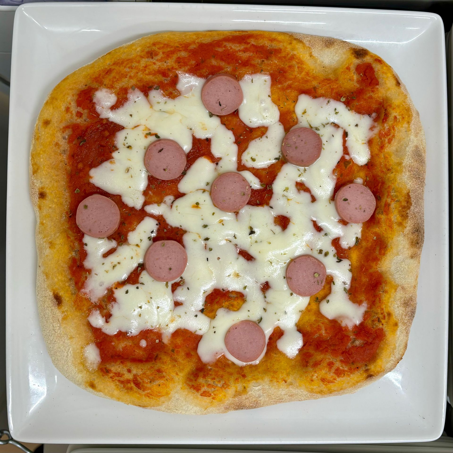 Una pizza con salsiccia e formaggio su un piatto bianco