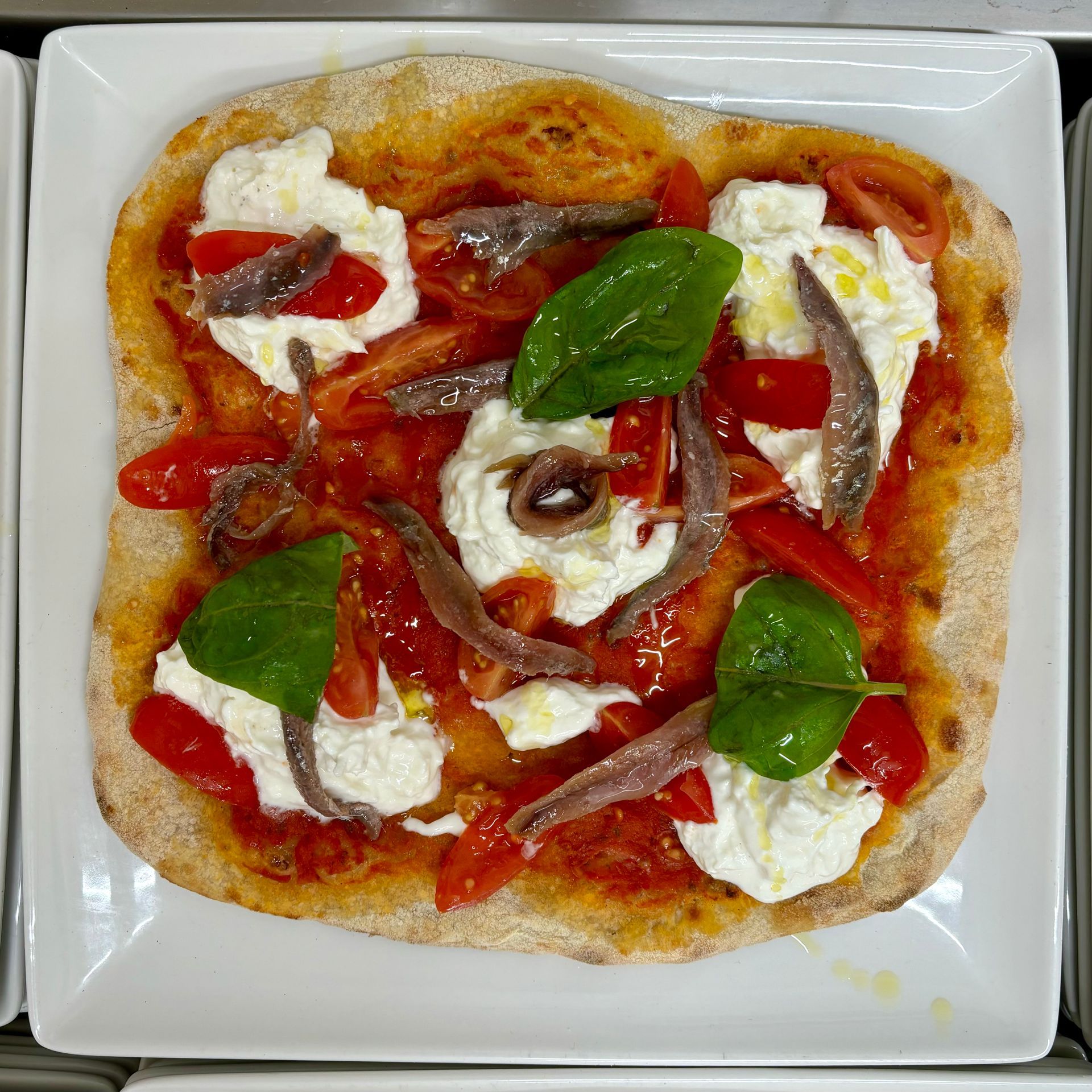 Una pizza con pomodori e basilico su un piatto bianco