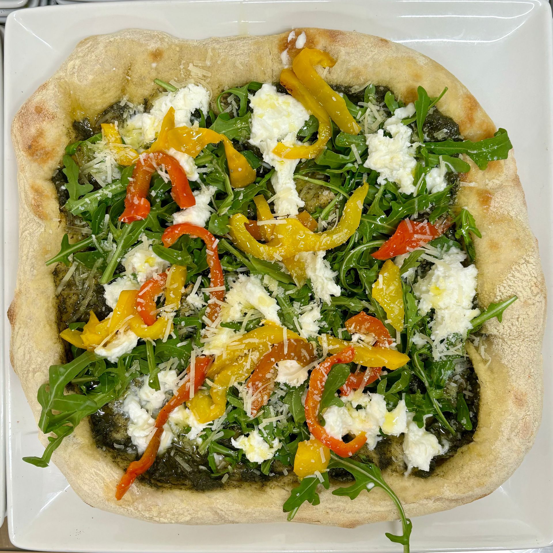 Una pizza con verdure e formaggio su un piatto bianco