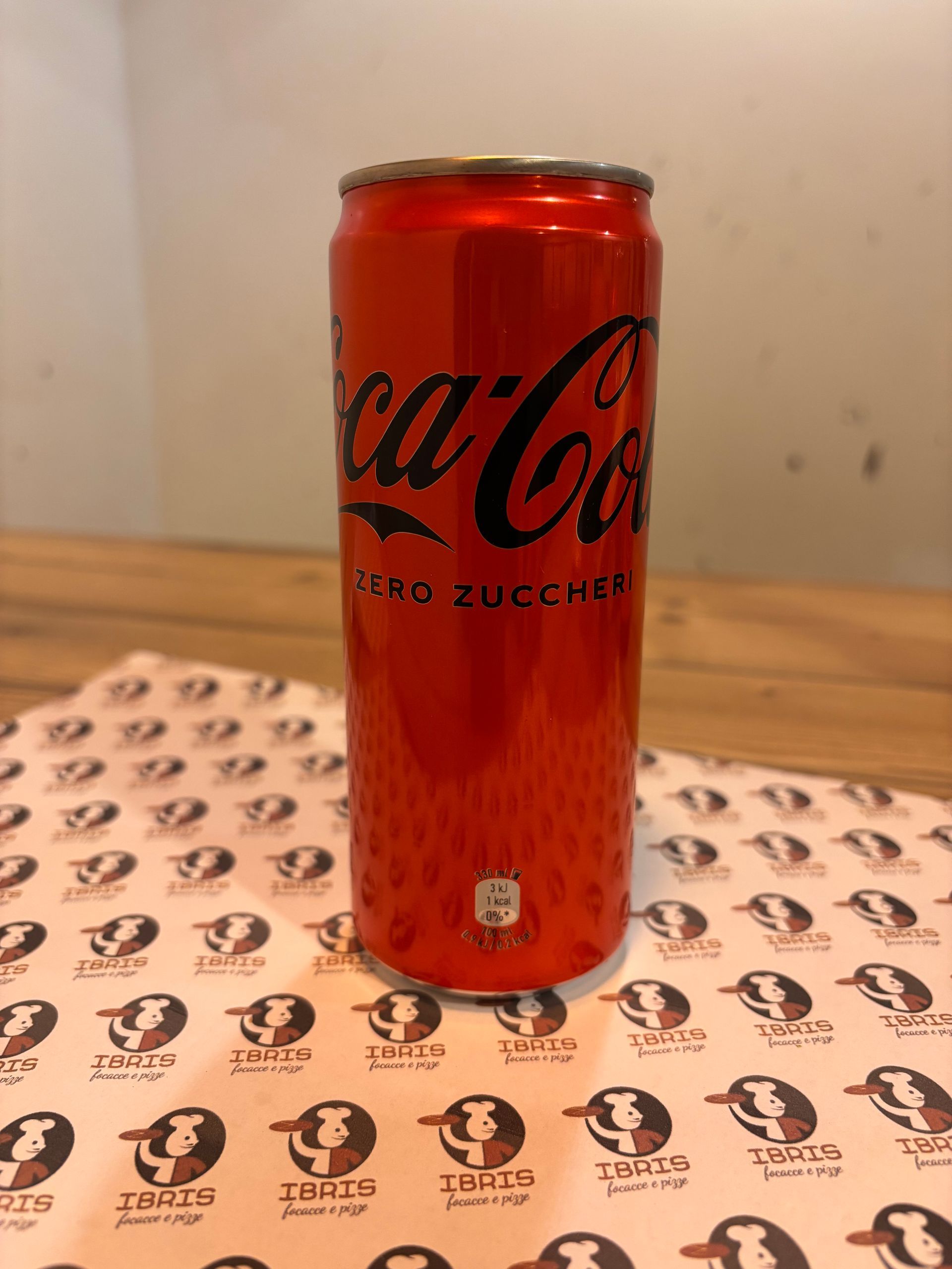 Una lattina rossa di coca cola è appoggiata su un tavolo