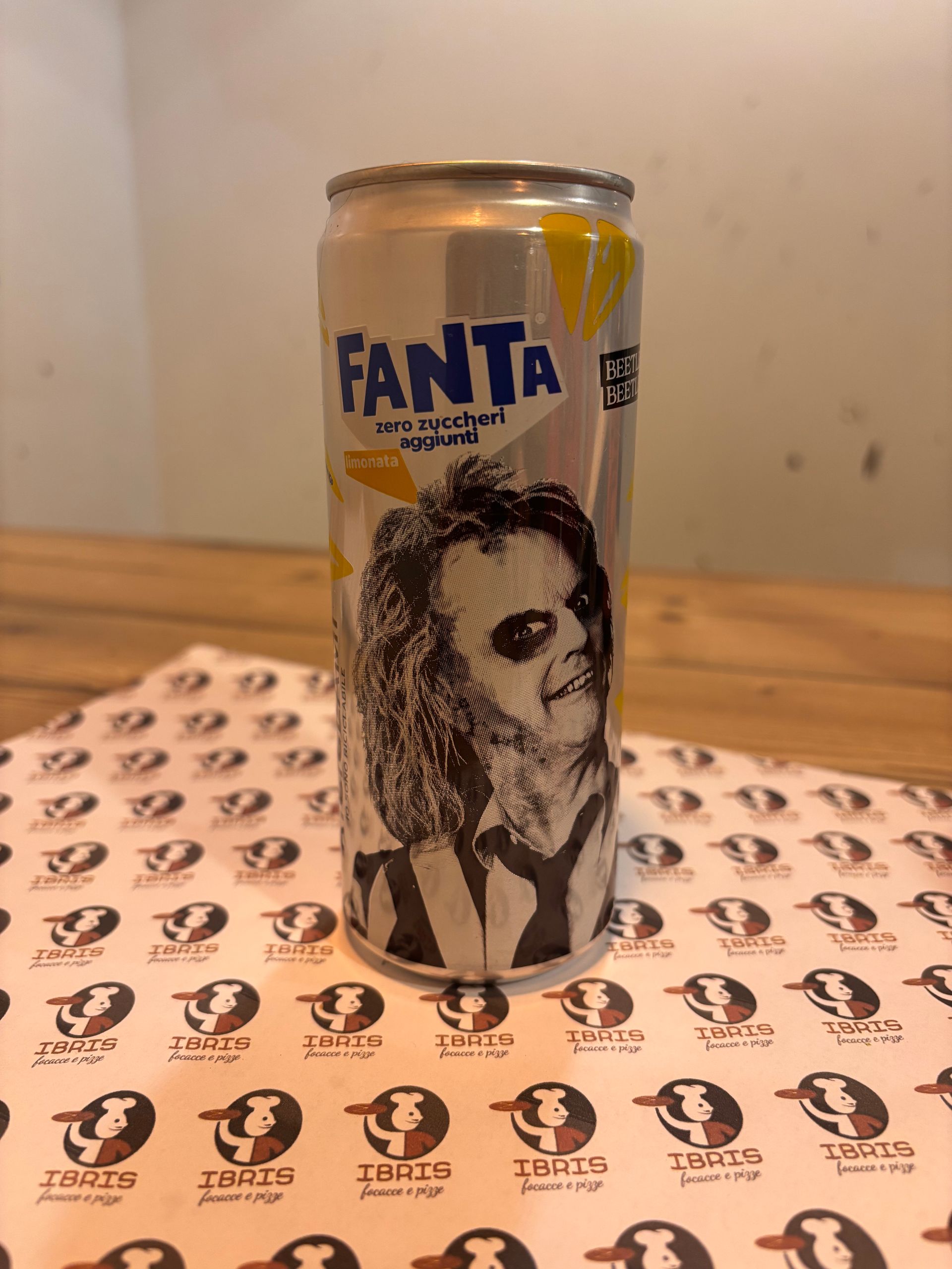 Una lattina di fanta con il disegno di un uomo sopra è appoggiata su un tavolo.