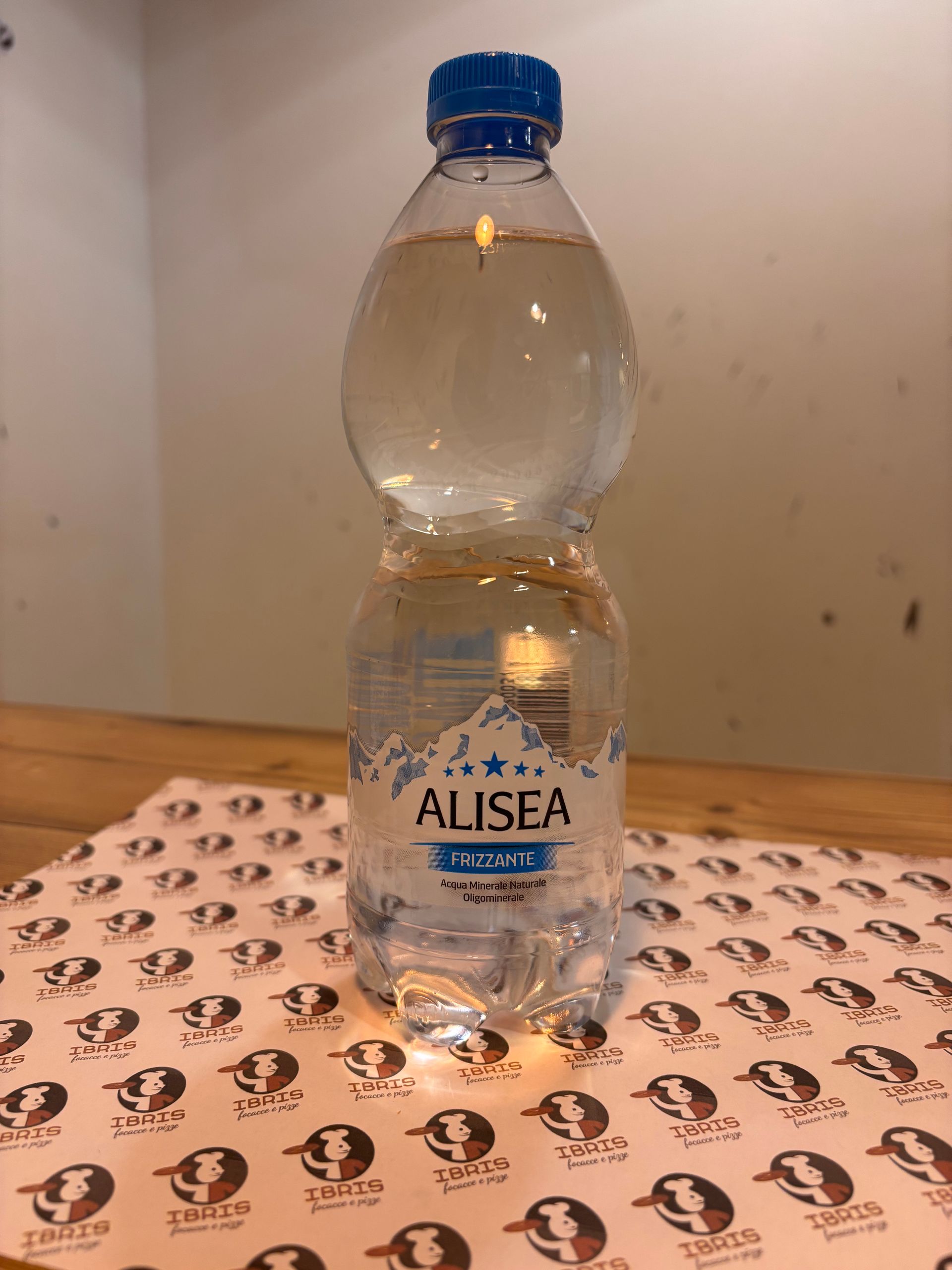 Una bottiglia di acqua Alisea è appoggiata su un tavolo.