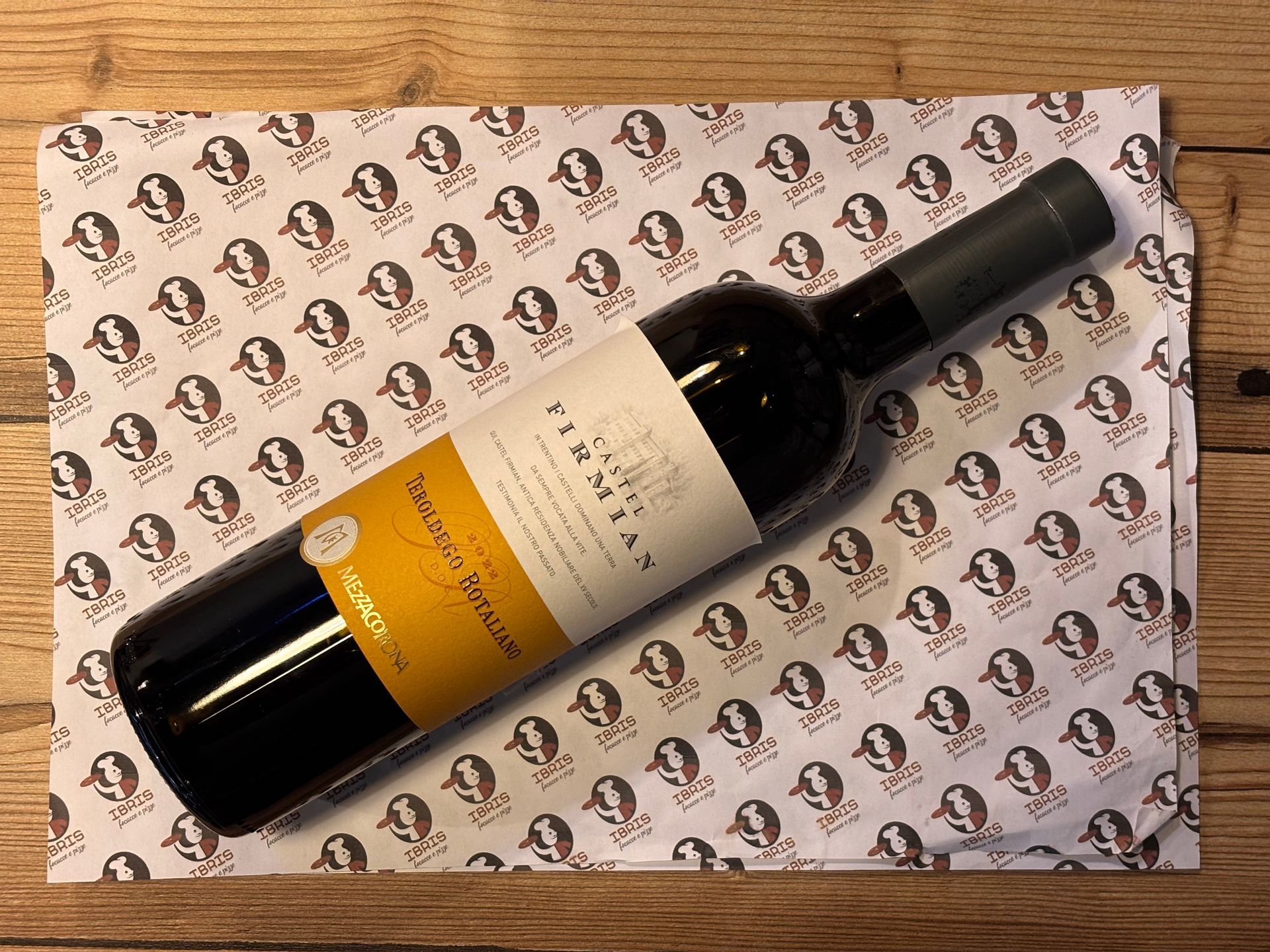 Una bottiglia di vino con un'etichetta gialla è appoggiata su una tovaglietta