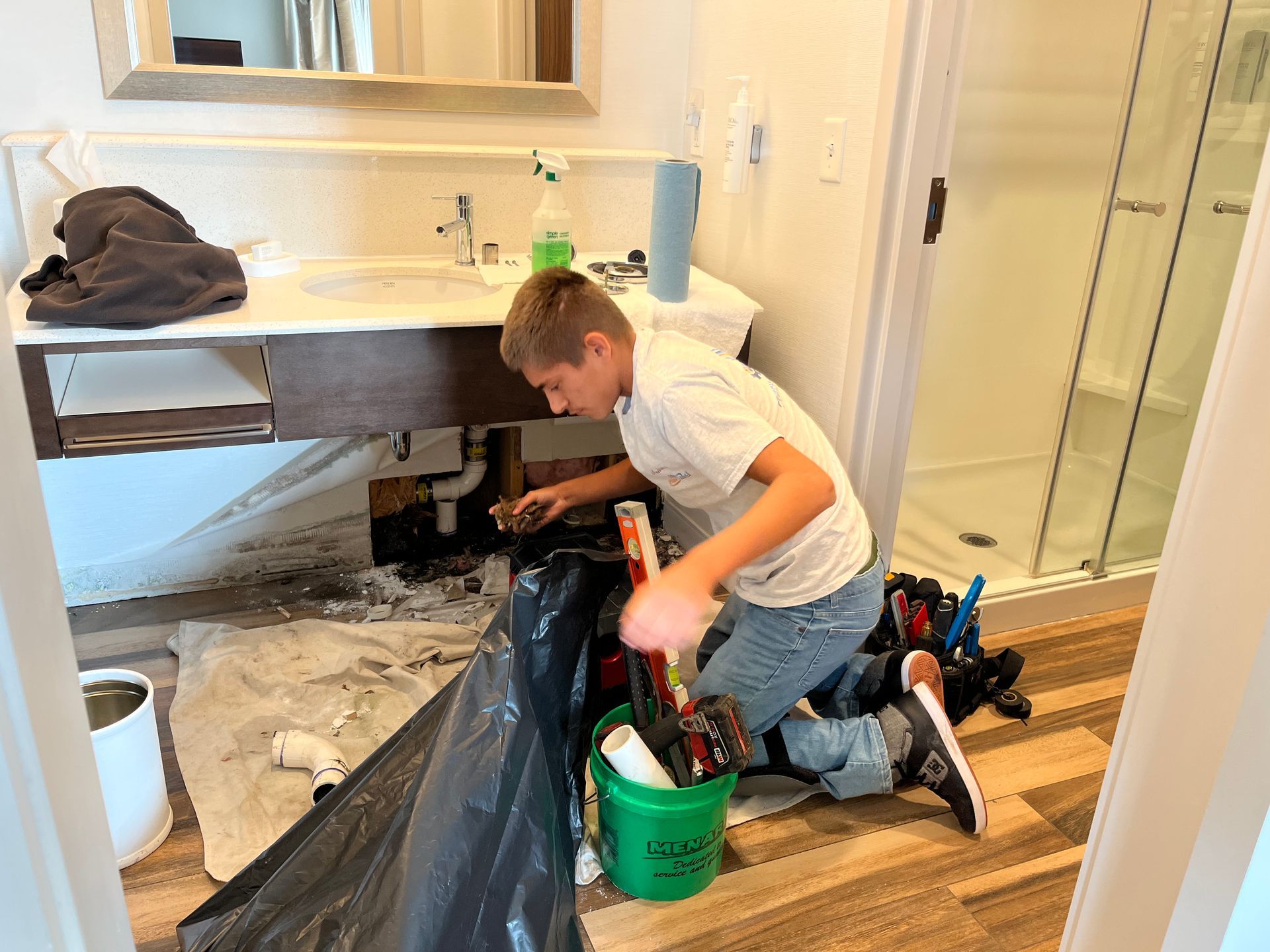 A young boy is fixing a sink in a bathroom.
