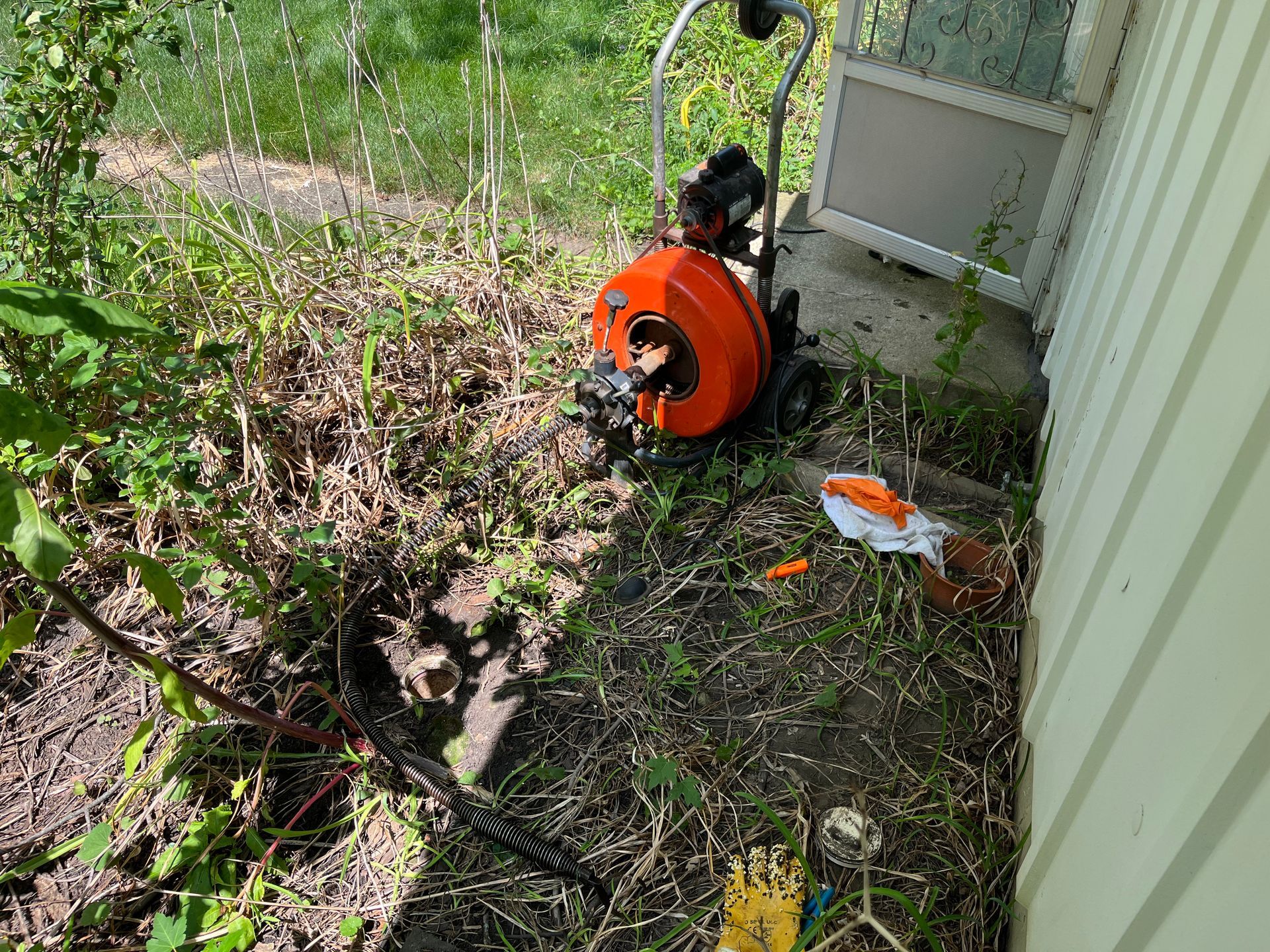 A hose reel is sitting on the ground next to a house.