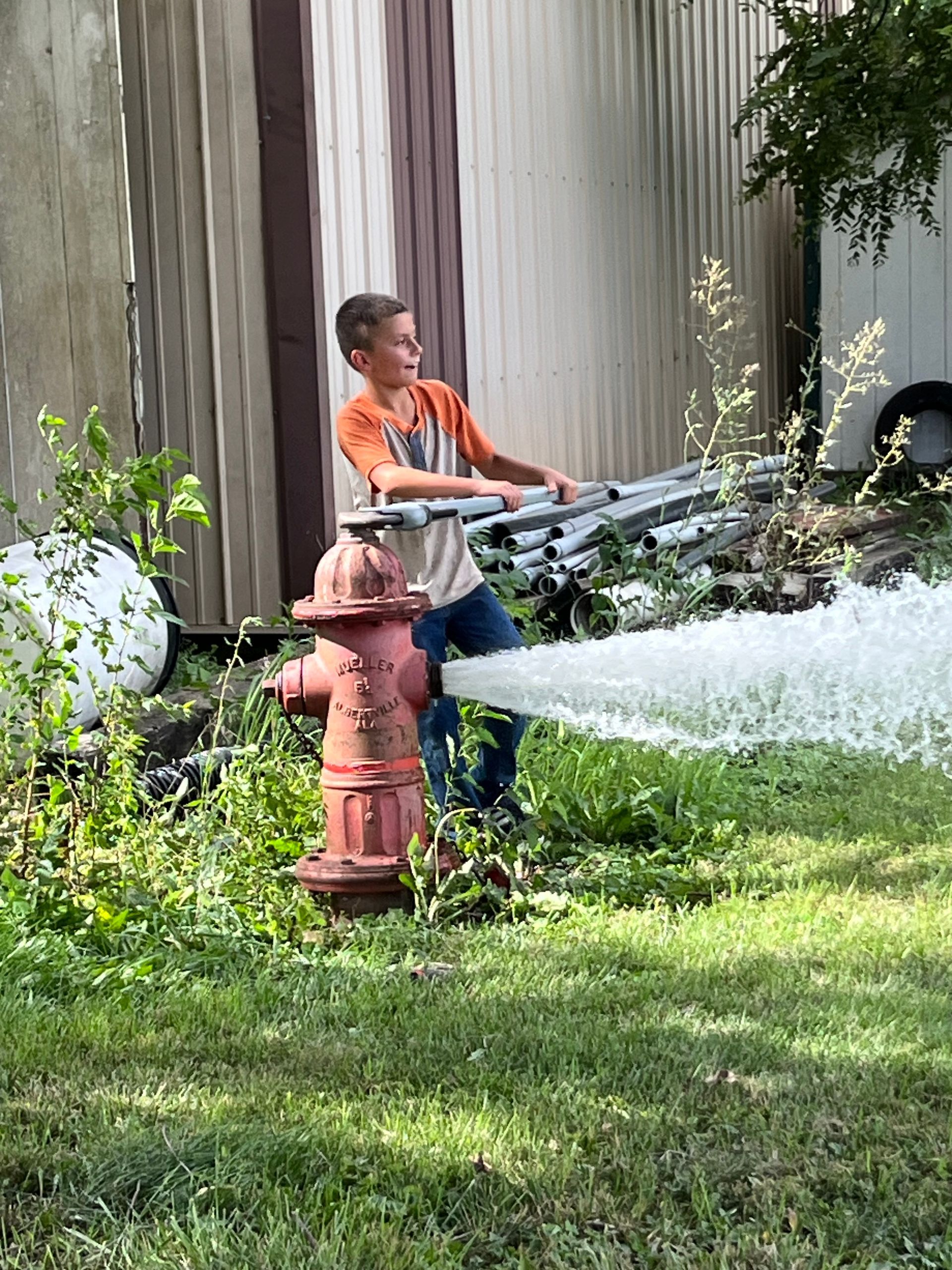 A young boy is spraying water from a fire hydrant.