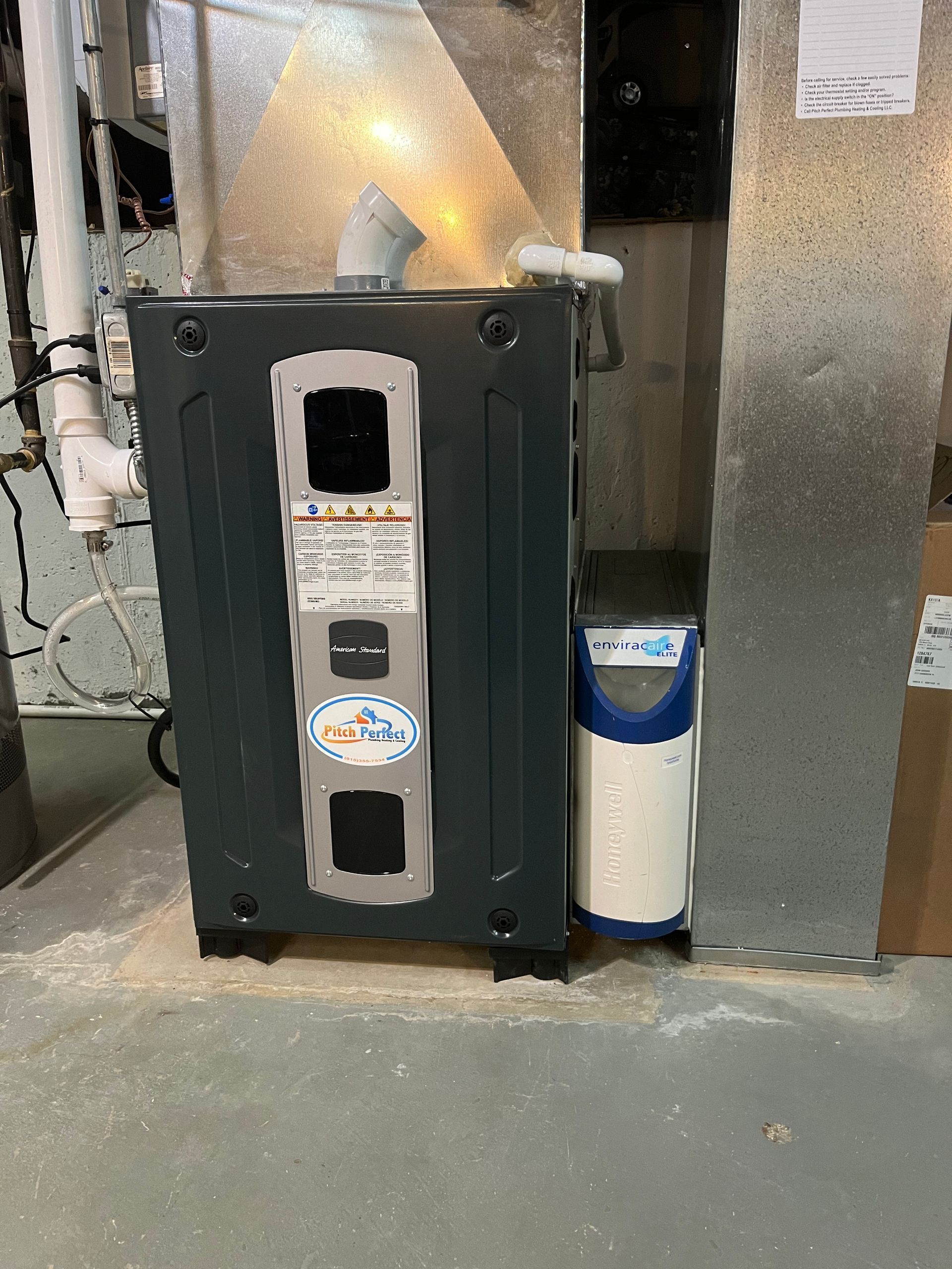 A gas heater is sitting in a basement next to a water filter.