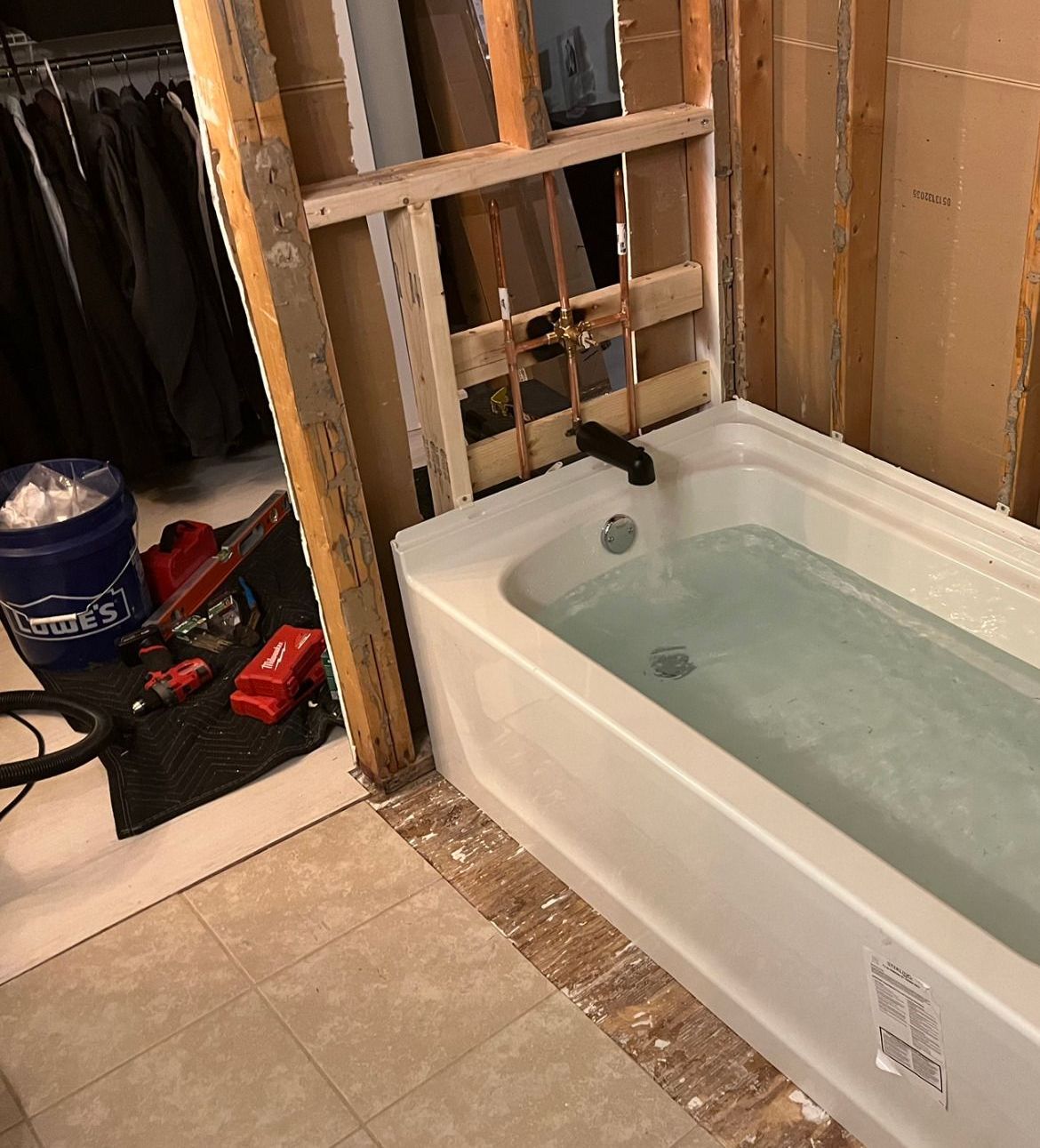 A bathtub filled with water in a bathroom under construction.