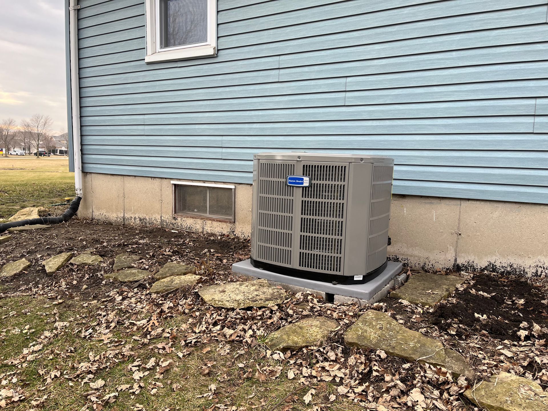 An air conditioner is sitting on the side of a house.