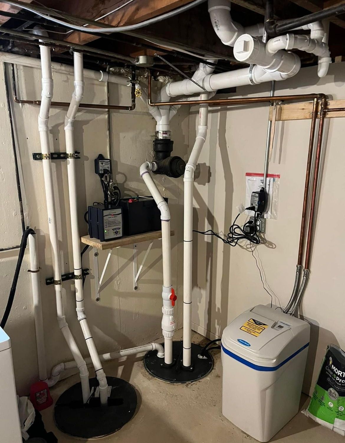 A basement with lots of pipes and a water softener.