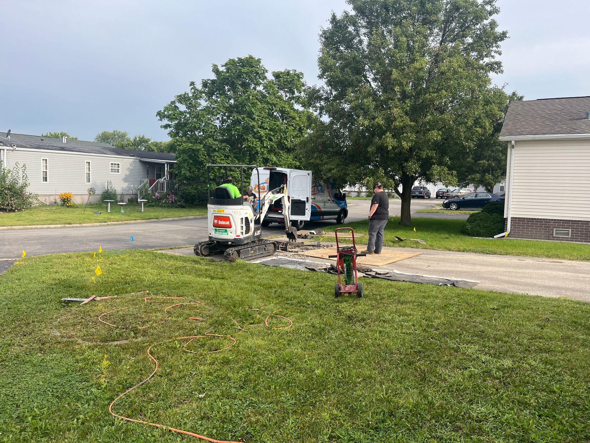 A group of people are working on a driveway in front of a house.