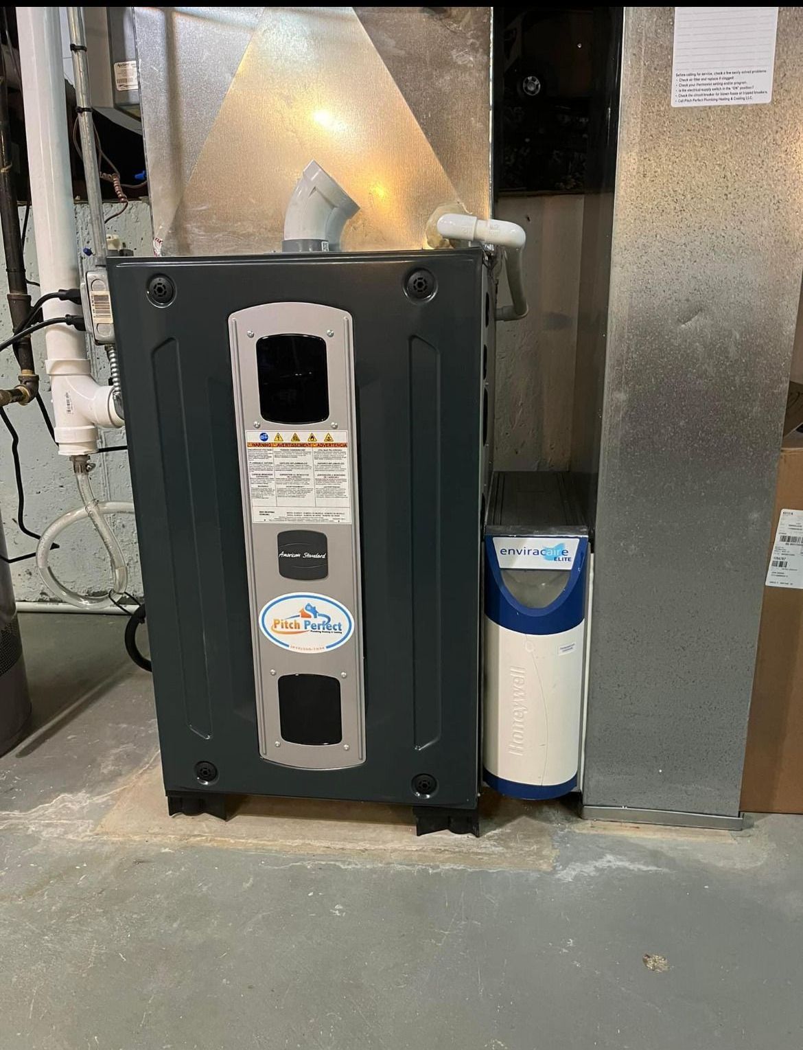 A furnace is sitting in a basement next to a water filter.