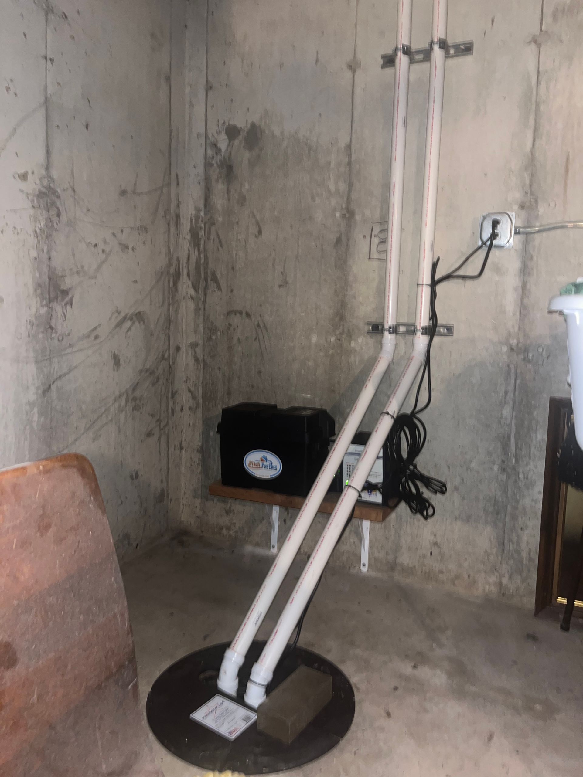 A basement with a sump pump and pipes in it.