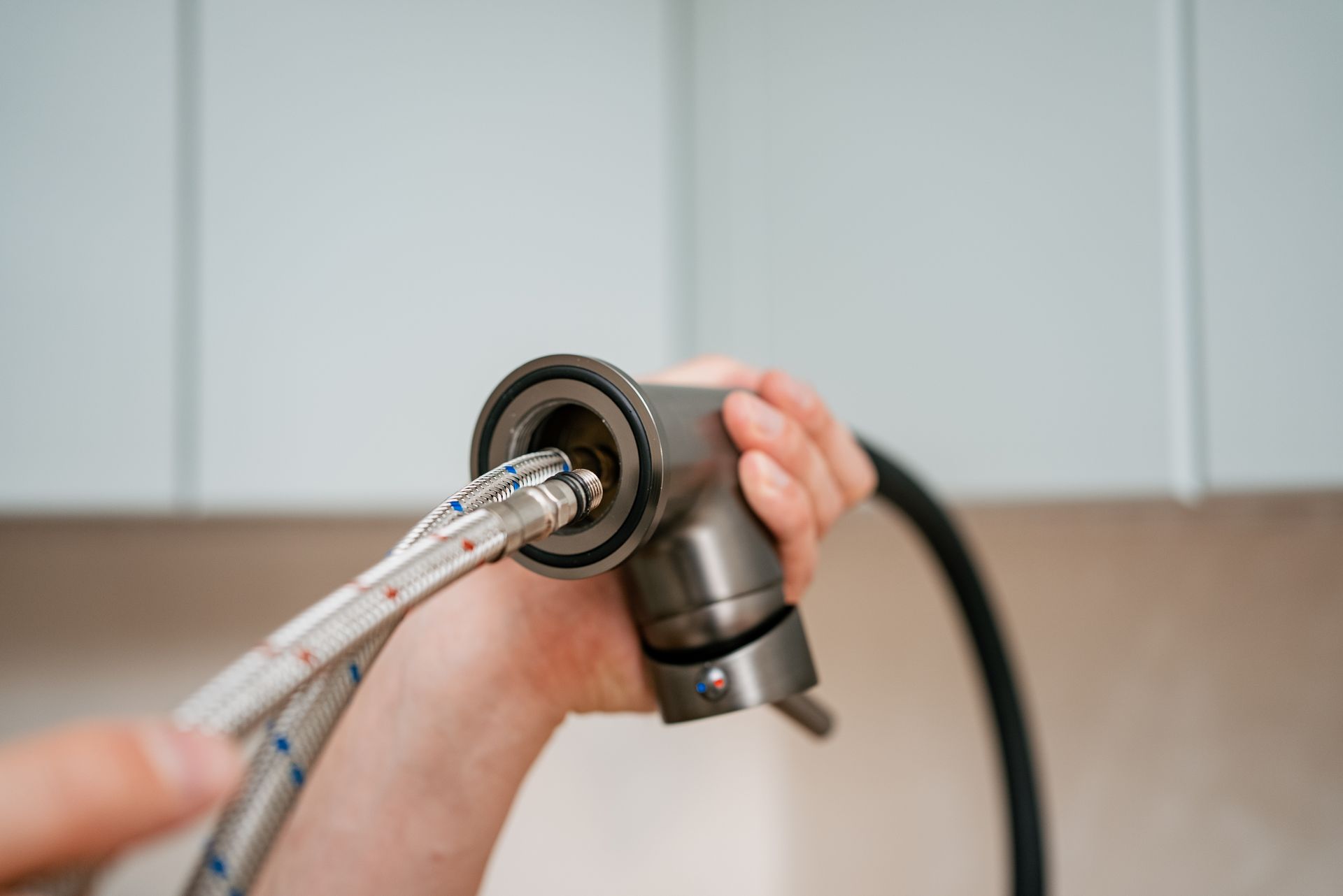Person attaching braided water lines to a kitchen faucet.