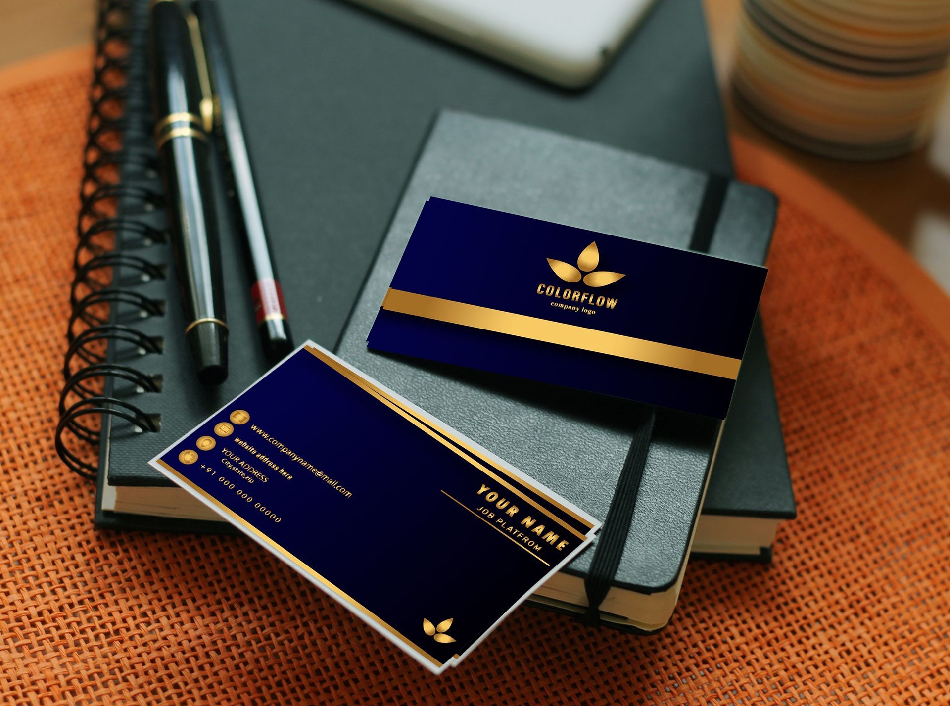 A business card sitting on top of a notebook next to a pen