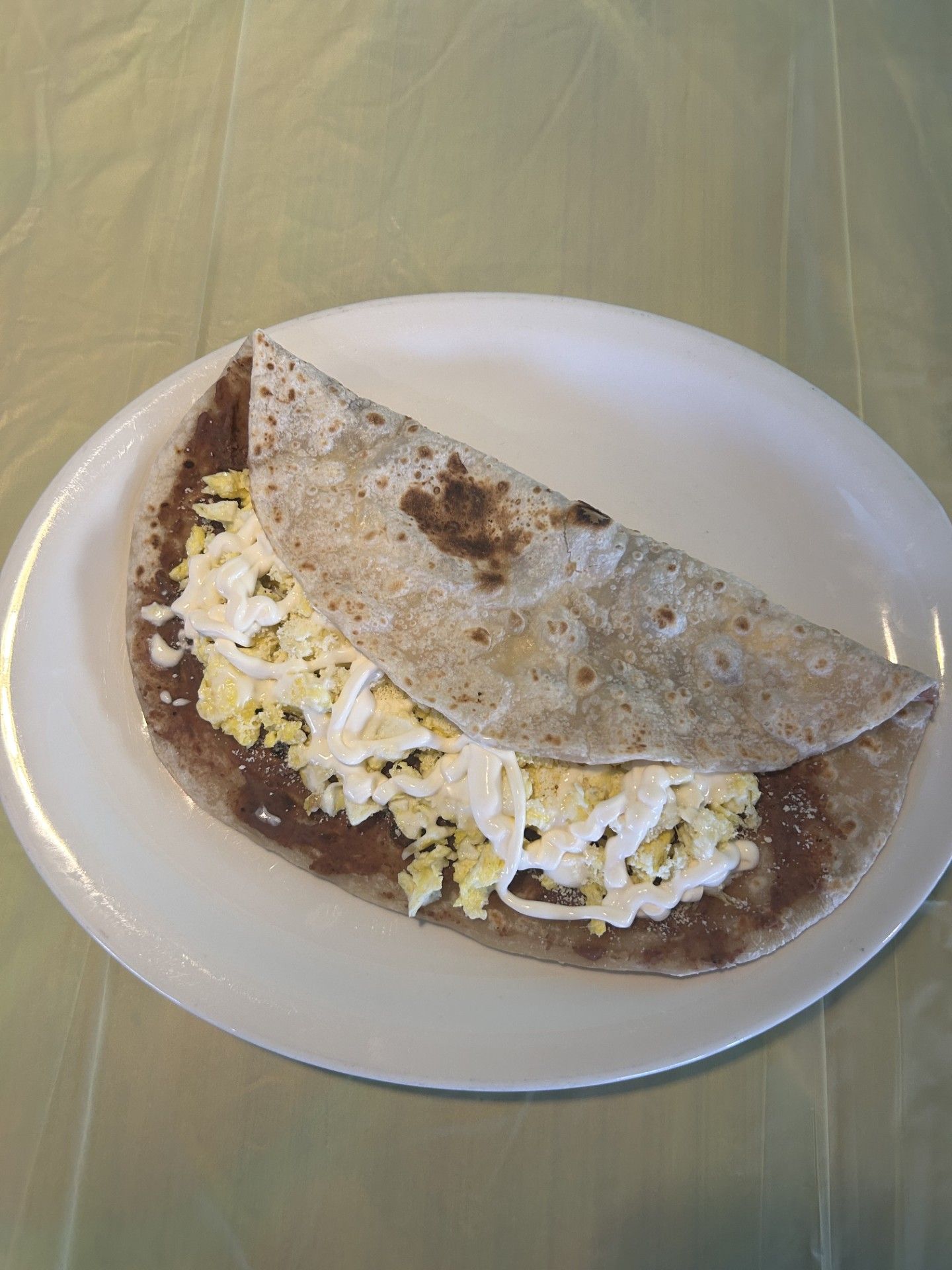 Tropical cocktail in a glass, with decorations, on a colorful table, near a door and fridge.