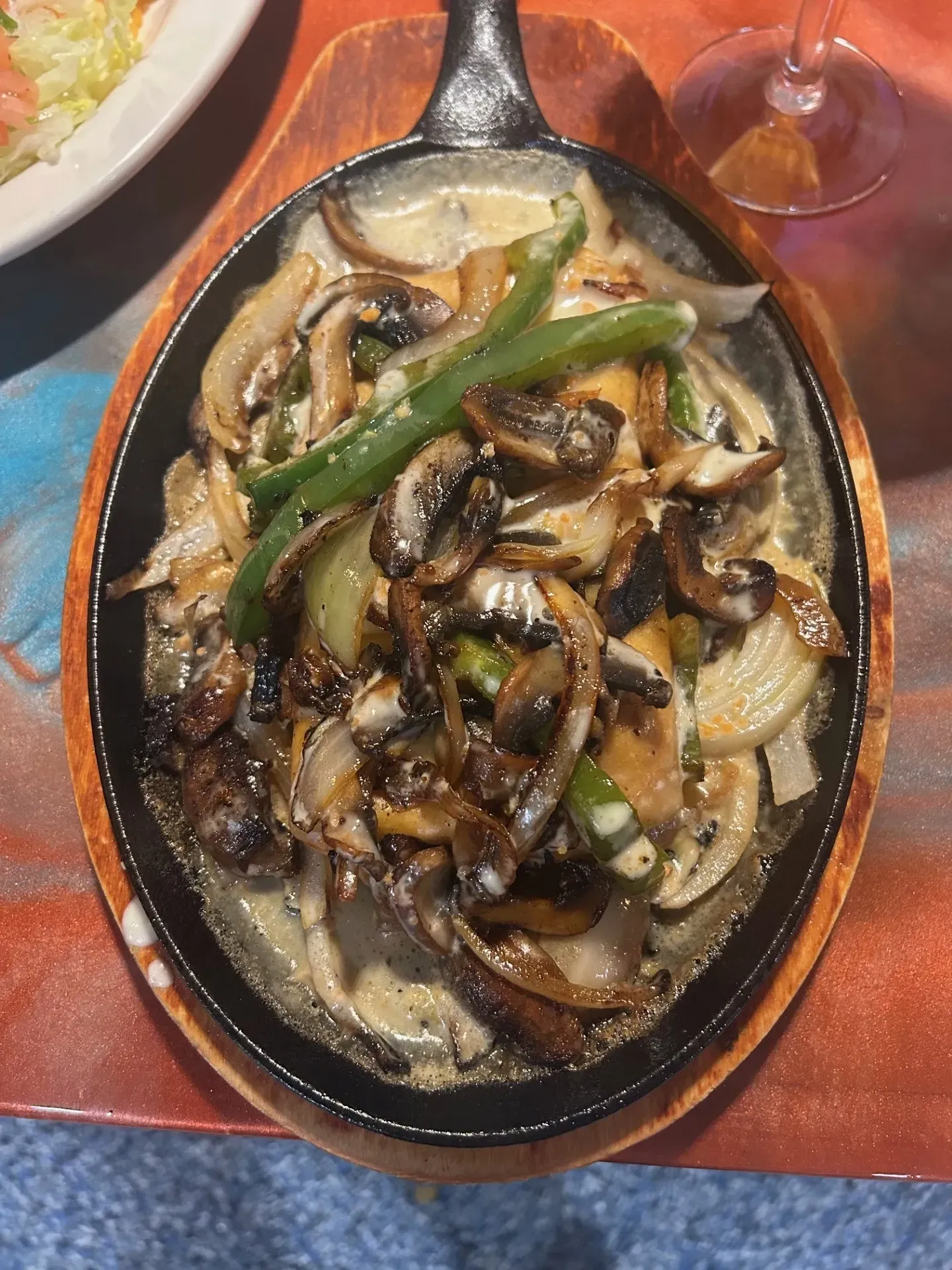 A skillet filled with mushrooms and green onions on a table.