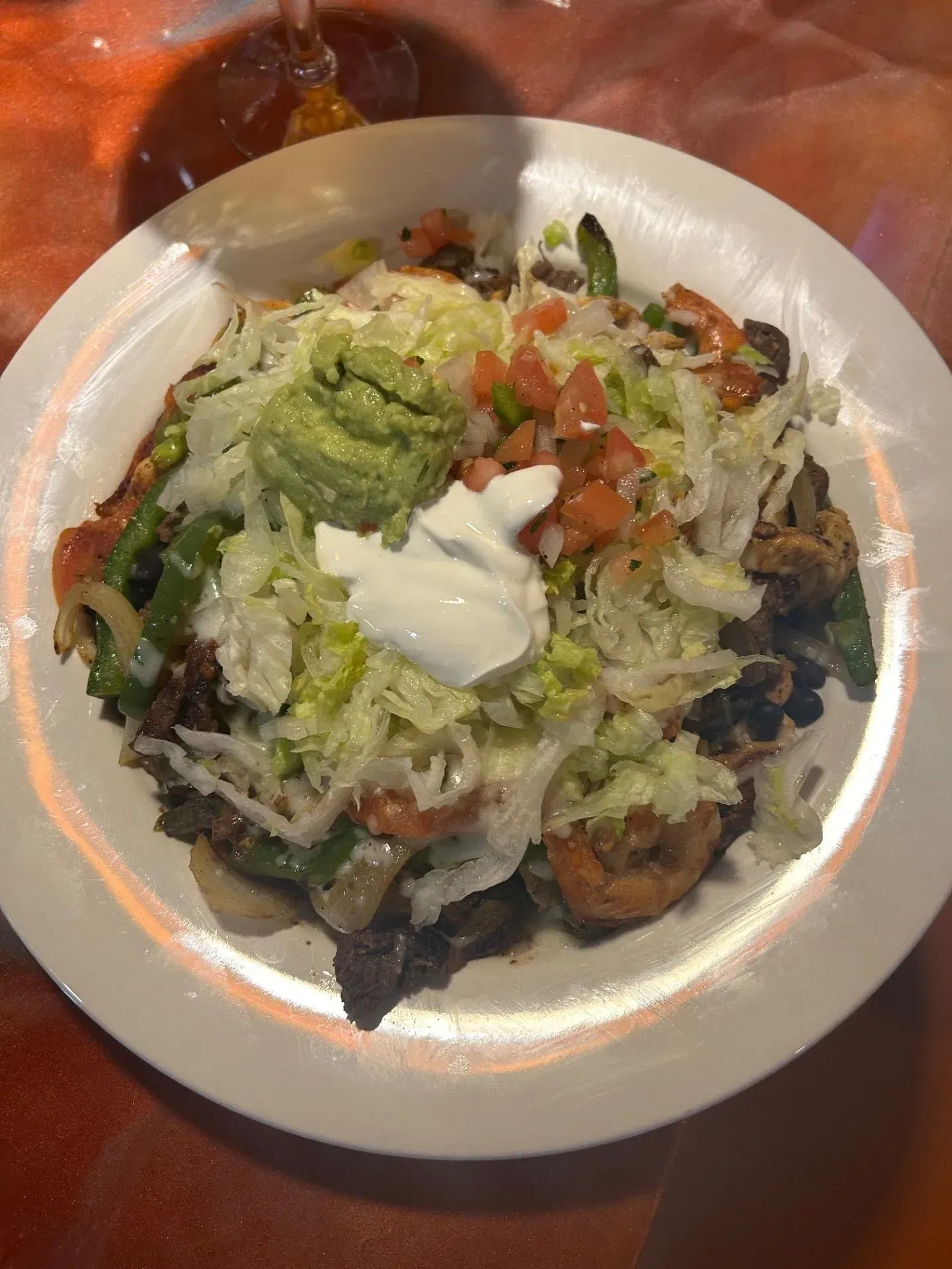 A close up of a plate of food with guacamole and sour cream on a table.