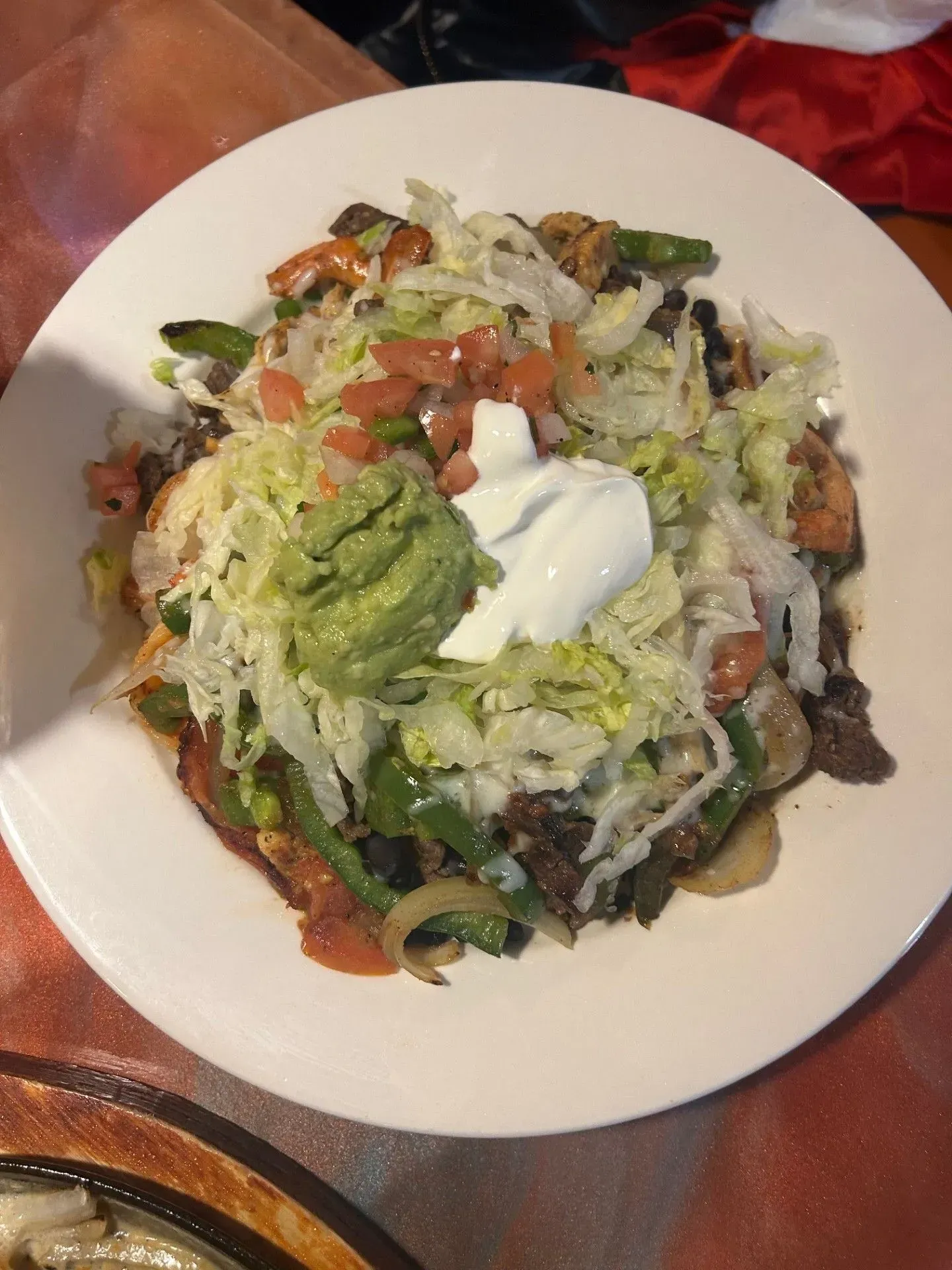A close up of a plate of food with guacamole and sour cream on a table.