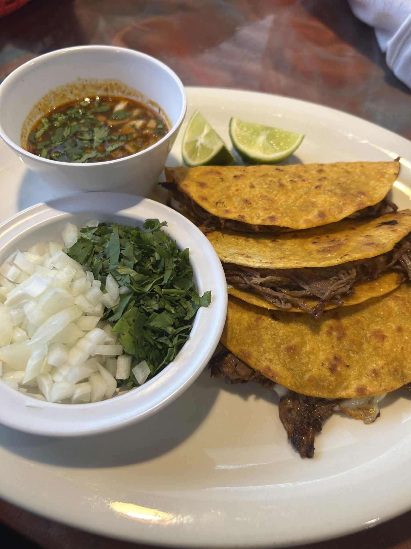 A white plate topped with tacos and a bowl of sauce.