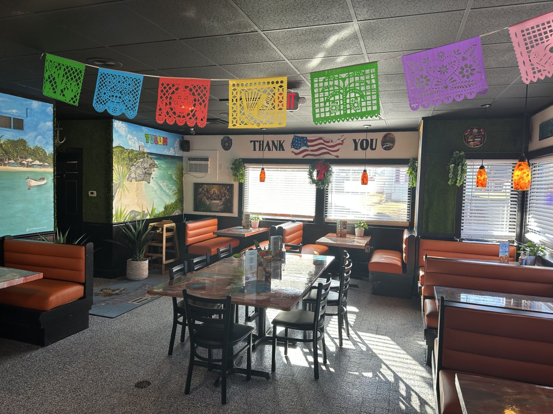 The inside of a restaurant with tables and chairs and paper flags hanging from the ceiling.