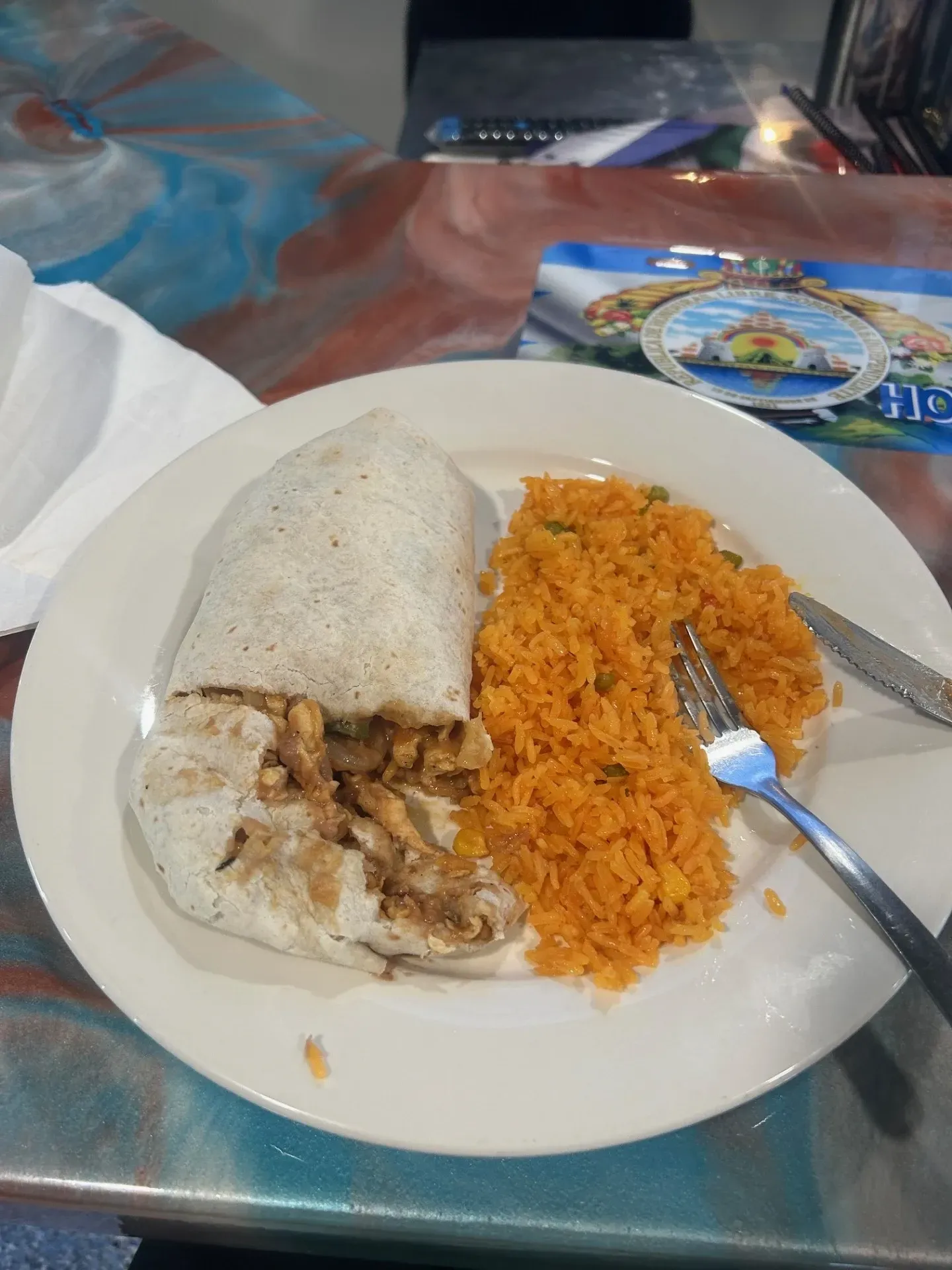 A plate of food with a burrito and rice on a table.