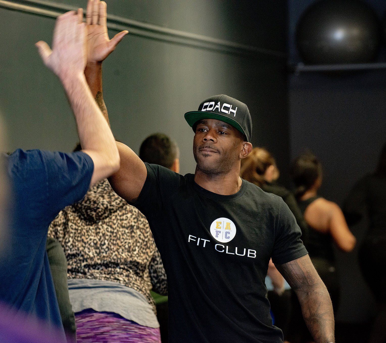 a man wearing a fit club shirt is giving a high five