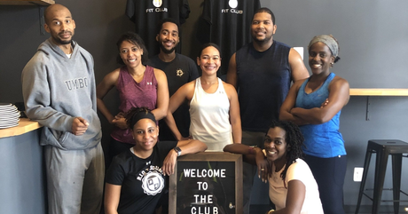 a group of people are posing for a picture in front of a sign that says welcome to the gym .