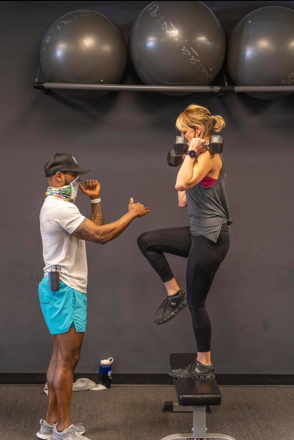a man is standing next to a woman on a bench in a gym .