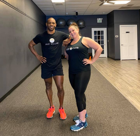 a man and a woman are posing for a picture in a gym wearing shirts that say fit club